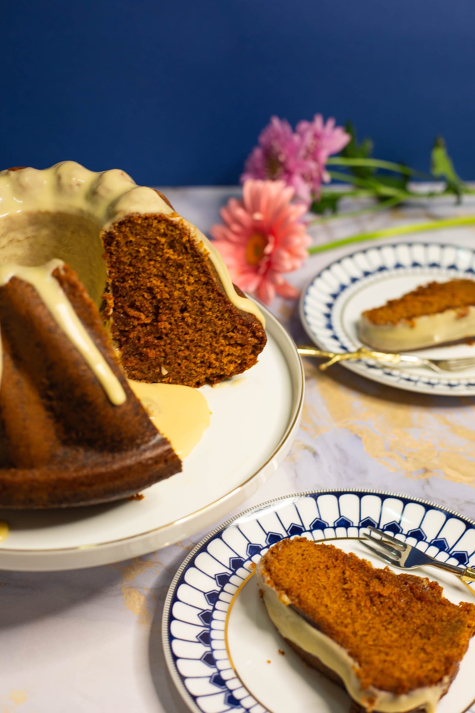 A cut rooibos and honey bundt with a slice on a blue and white plate in front