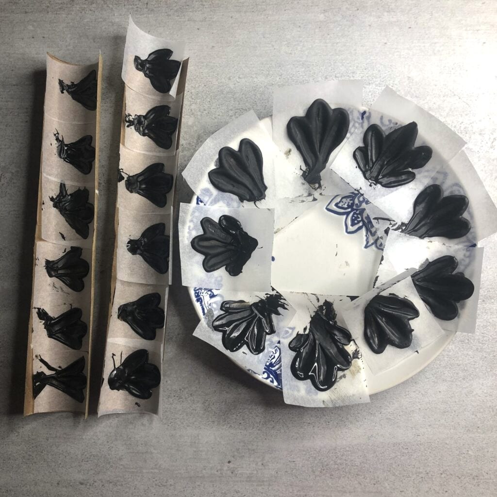 Chocolate petals setting on squares of baking paper, cupped inside the halved paper towel holders and arranged in a ring around the side plate