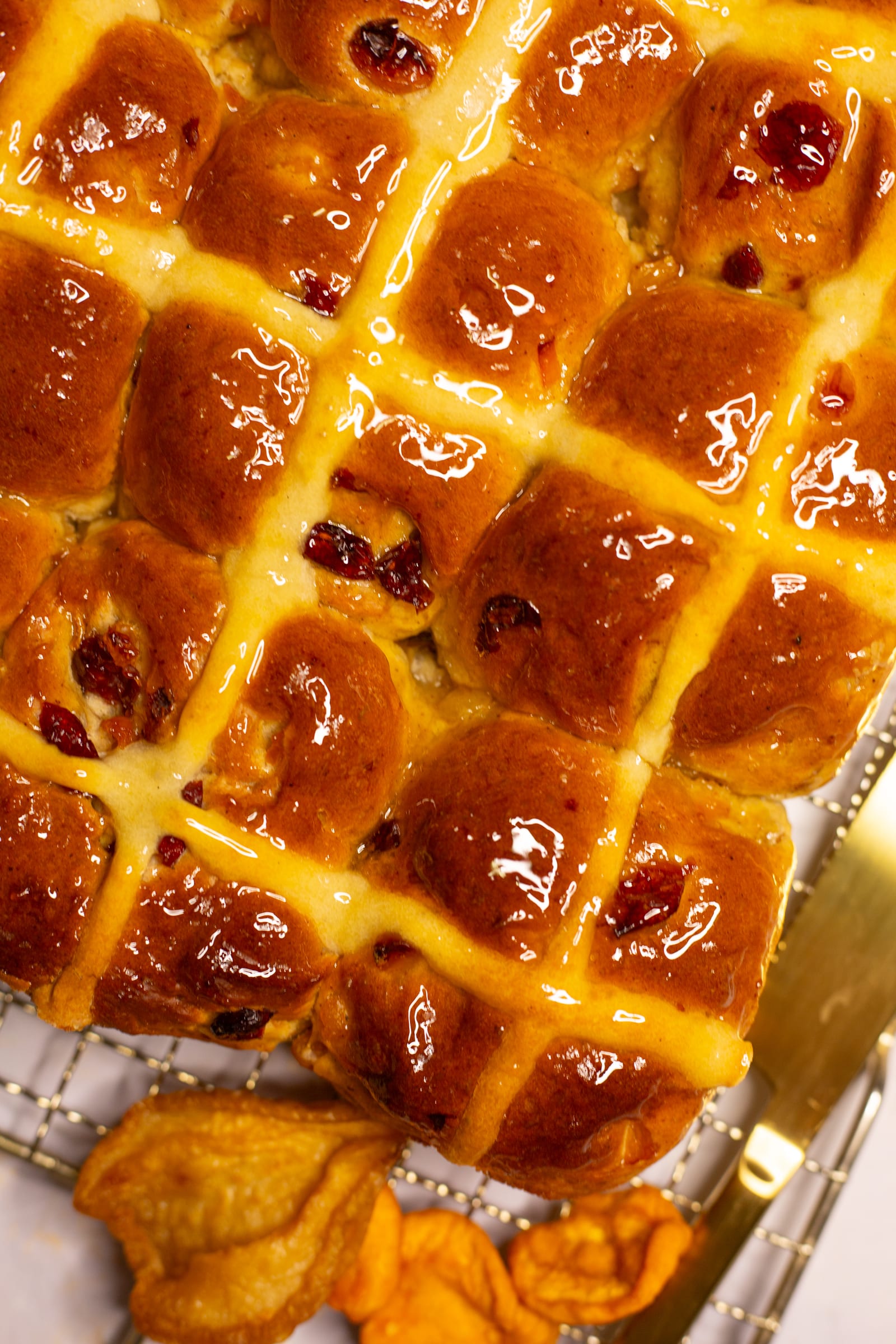 Close-up of the glossy apricot and cranberry hot cross buns and their piped crosses