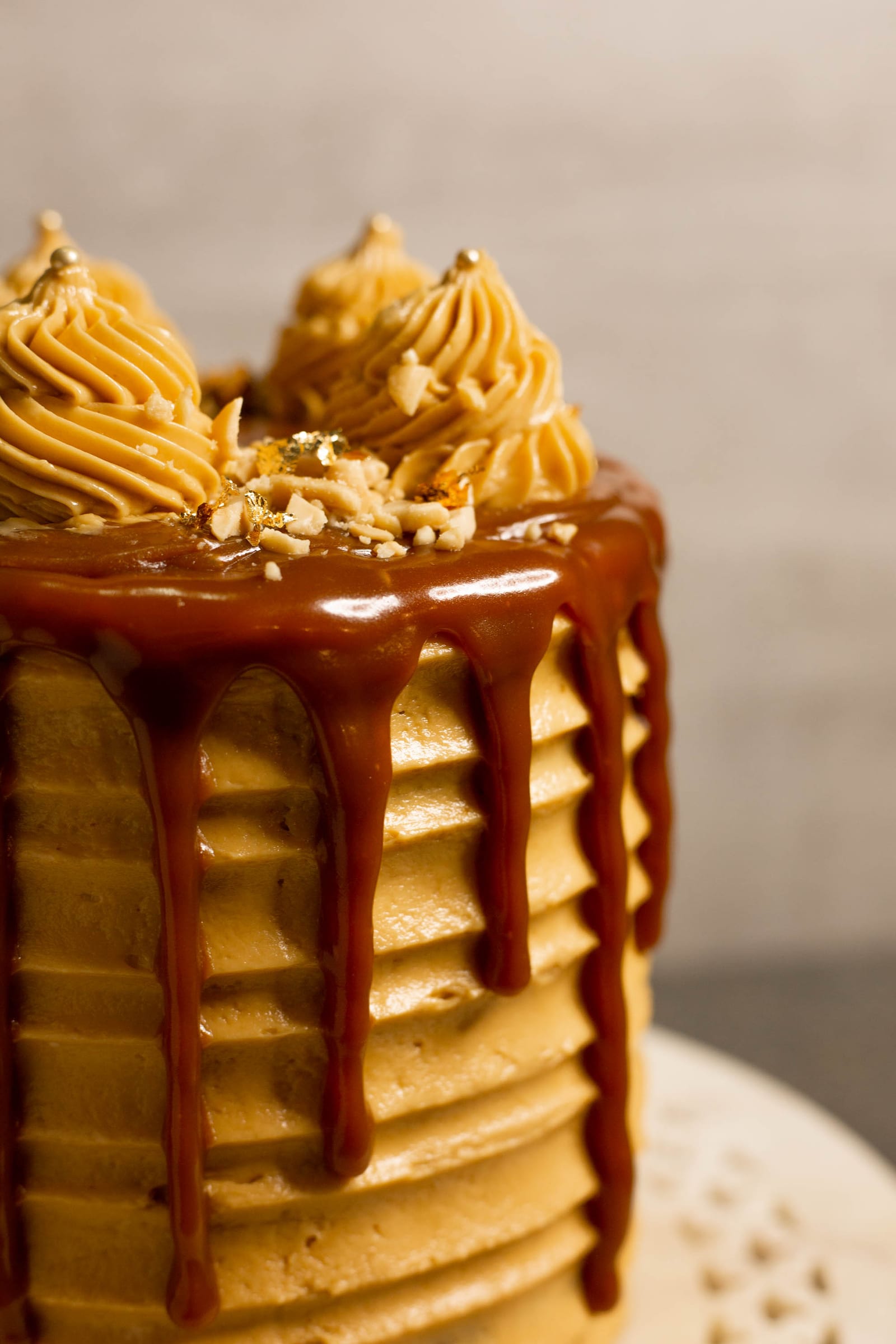 Close-up of the ridged buttercream sides and caramel drip of a salted caramel peanut cake