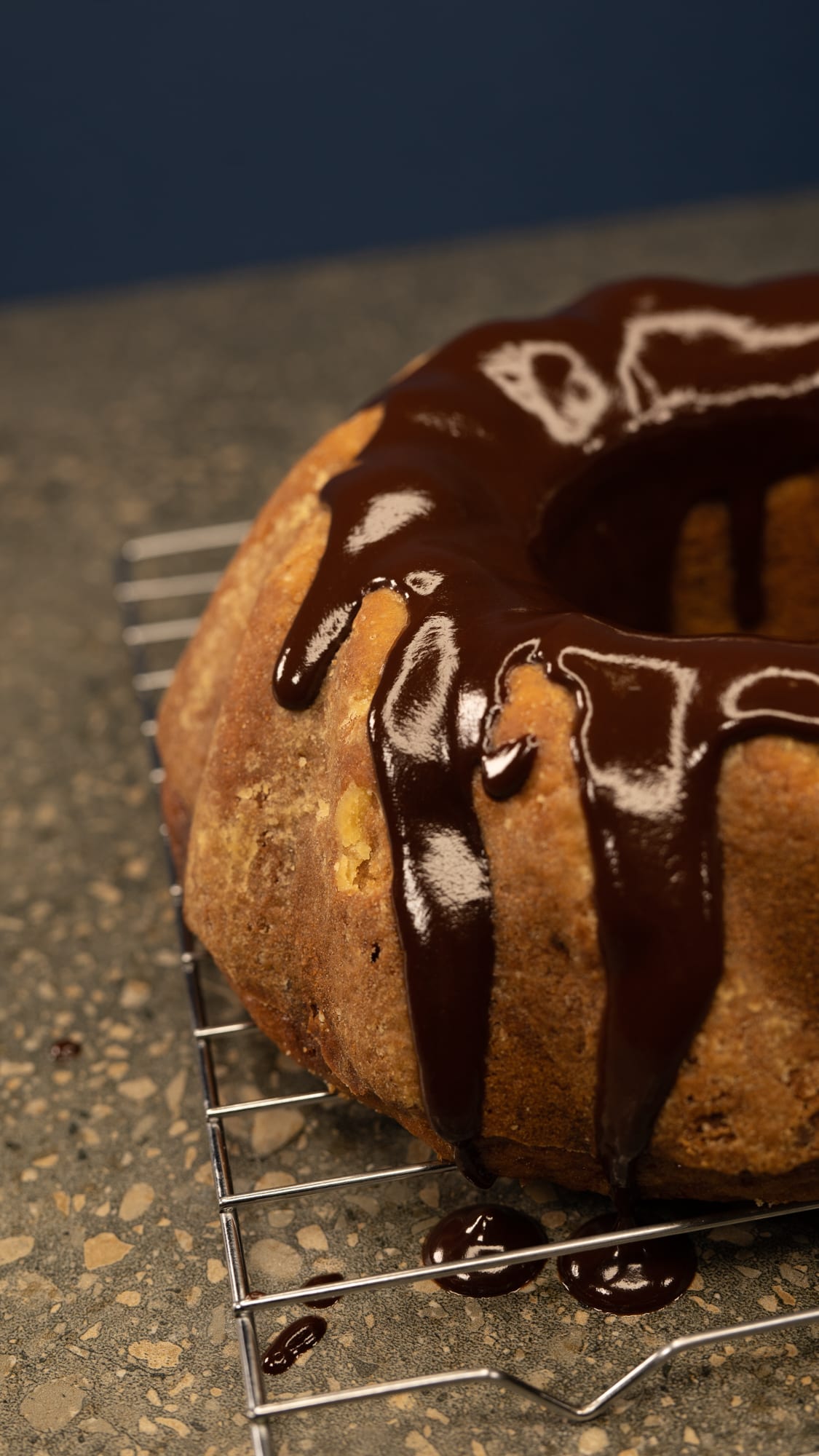Glossy water ganache dripping down a banana cake on a wire rack