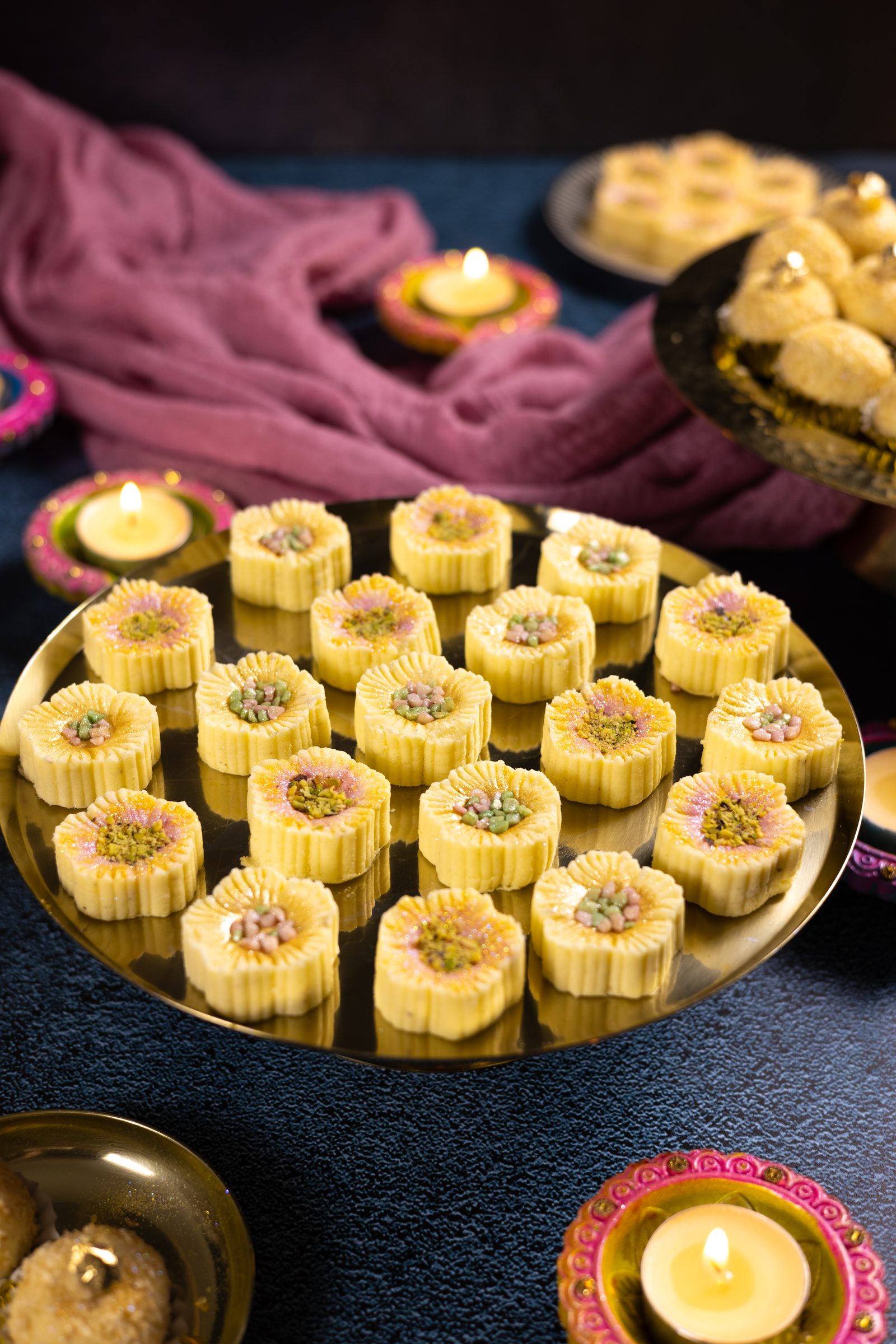 A gold stand of flower-shaped simply wonderfuls topped with pistachios and coloured almonds, from the side