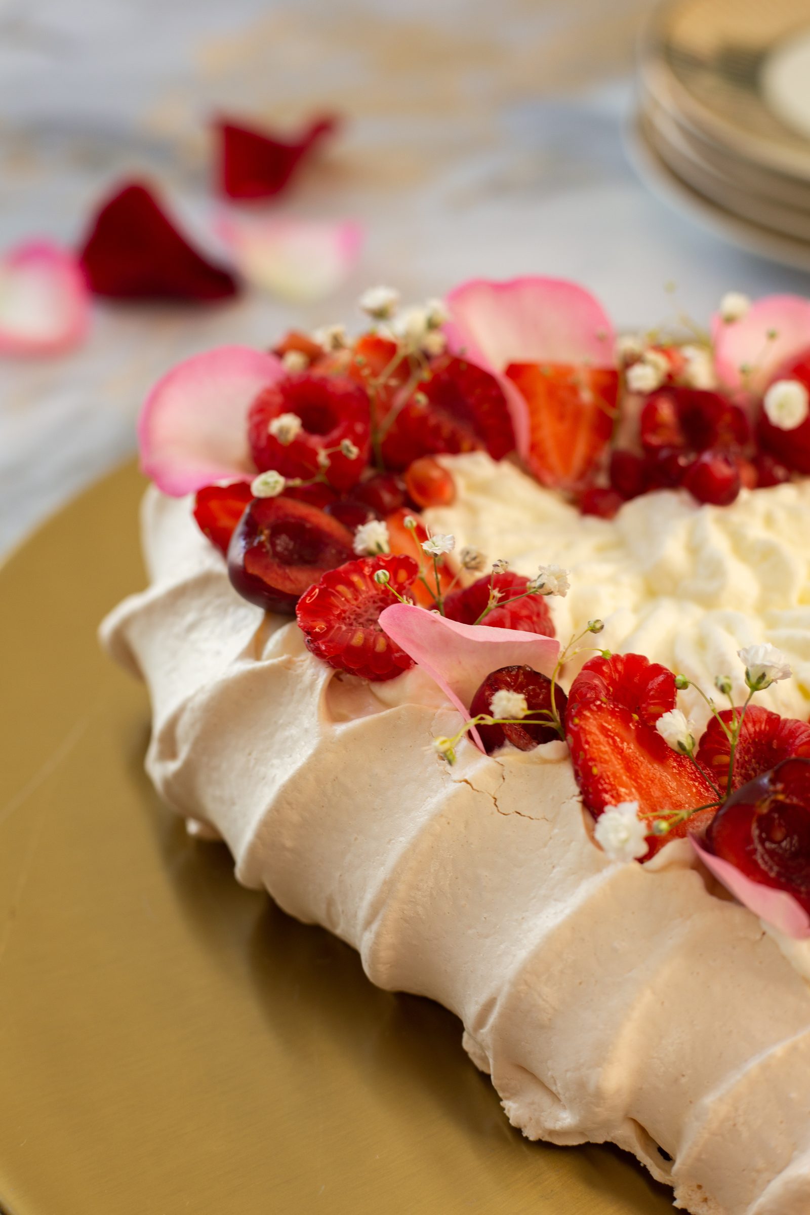 The crisp ridged meringue shell of a berry pavlova under the berries, close up from the side