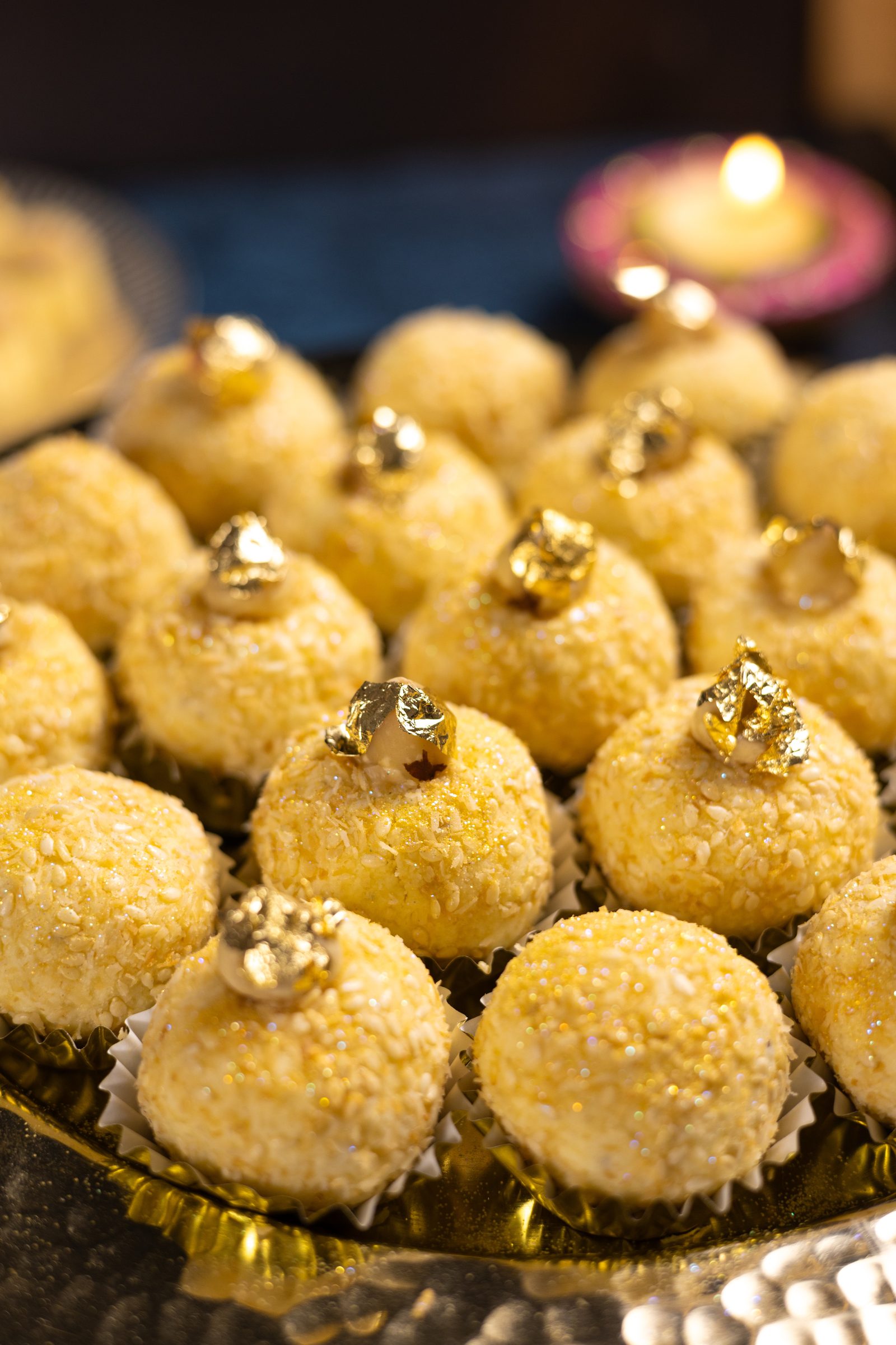 Close-up of coconut Simply Wonderfuls in paper cases, each topped with a piece of gold leaf