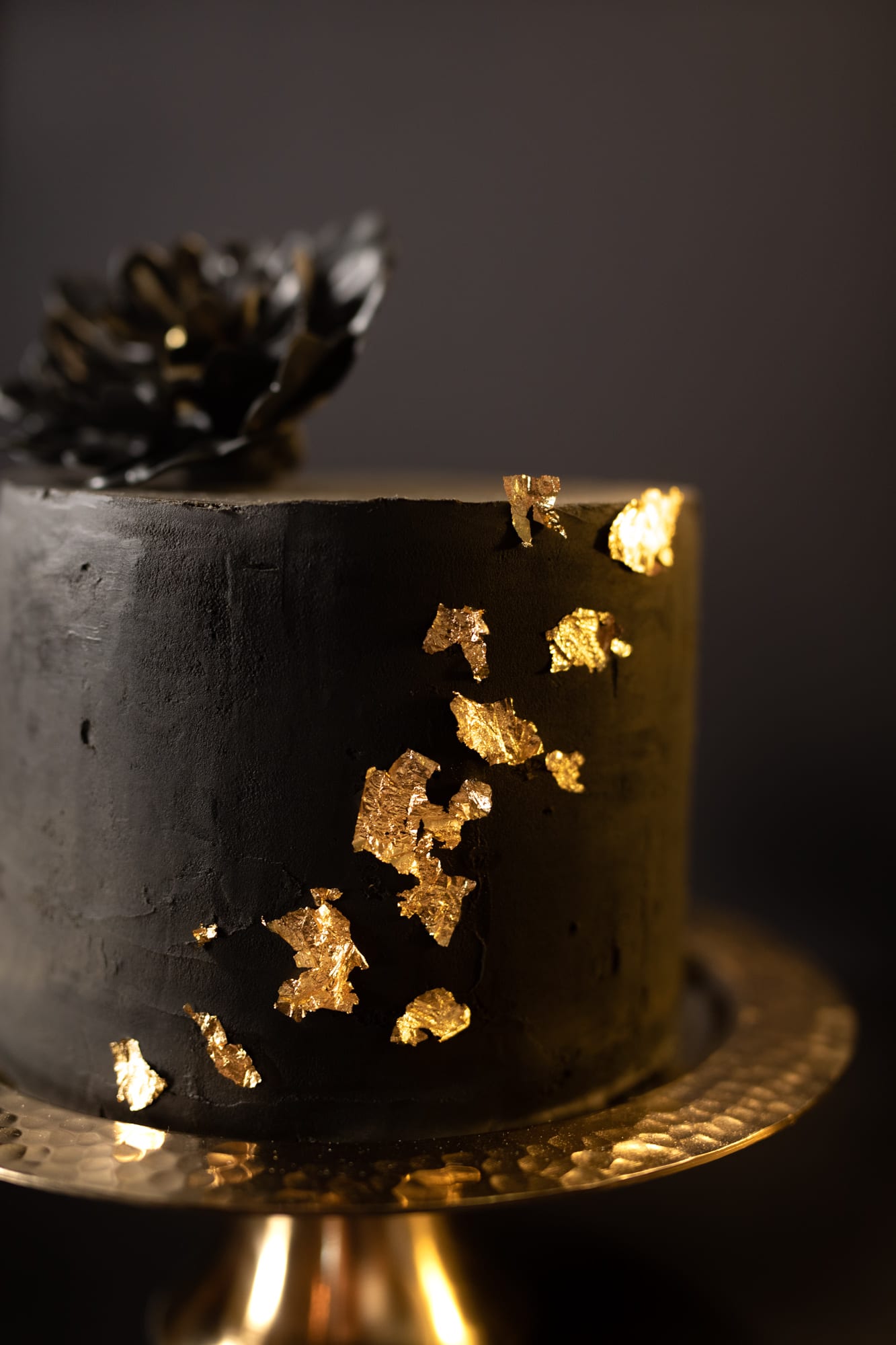 Close-up of the side of a black velvet cake with flecks of gold leaf