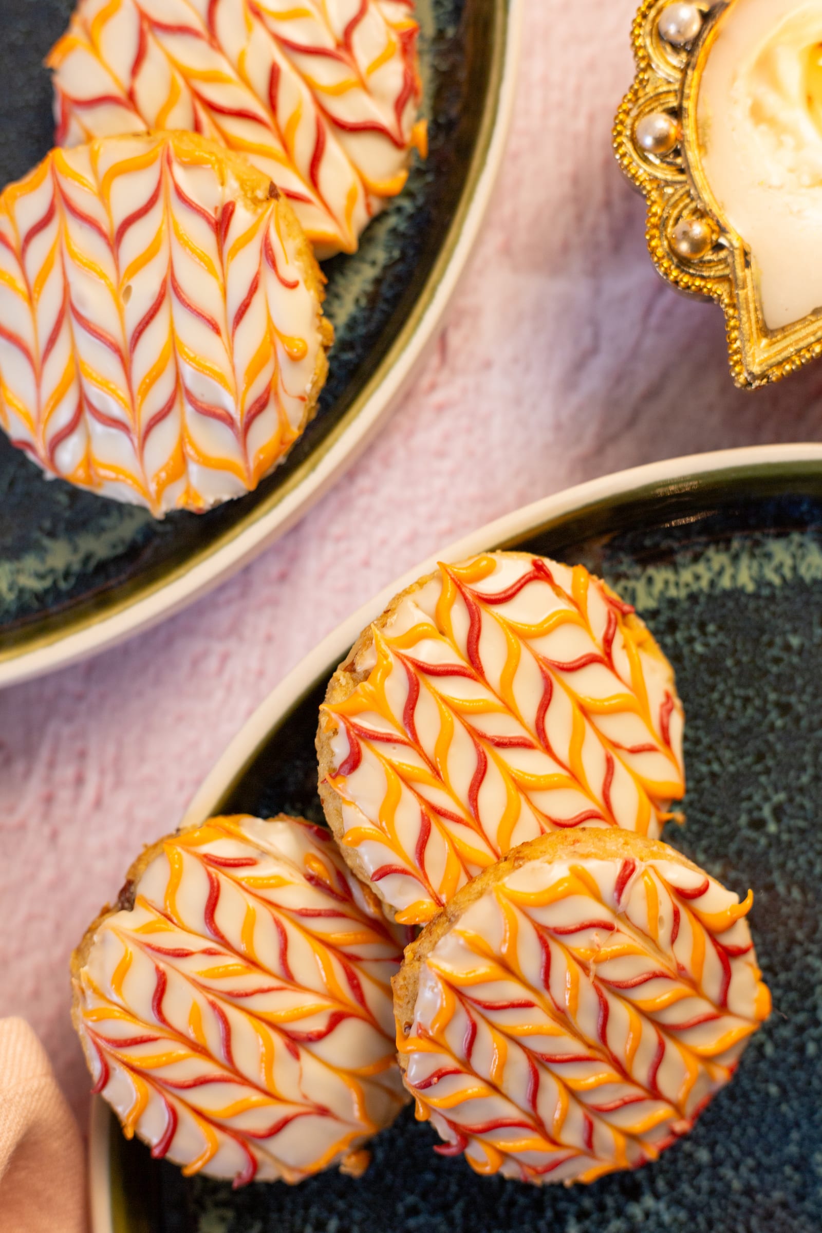 Two coconut and almond biscuits beside a gold diya