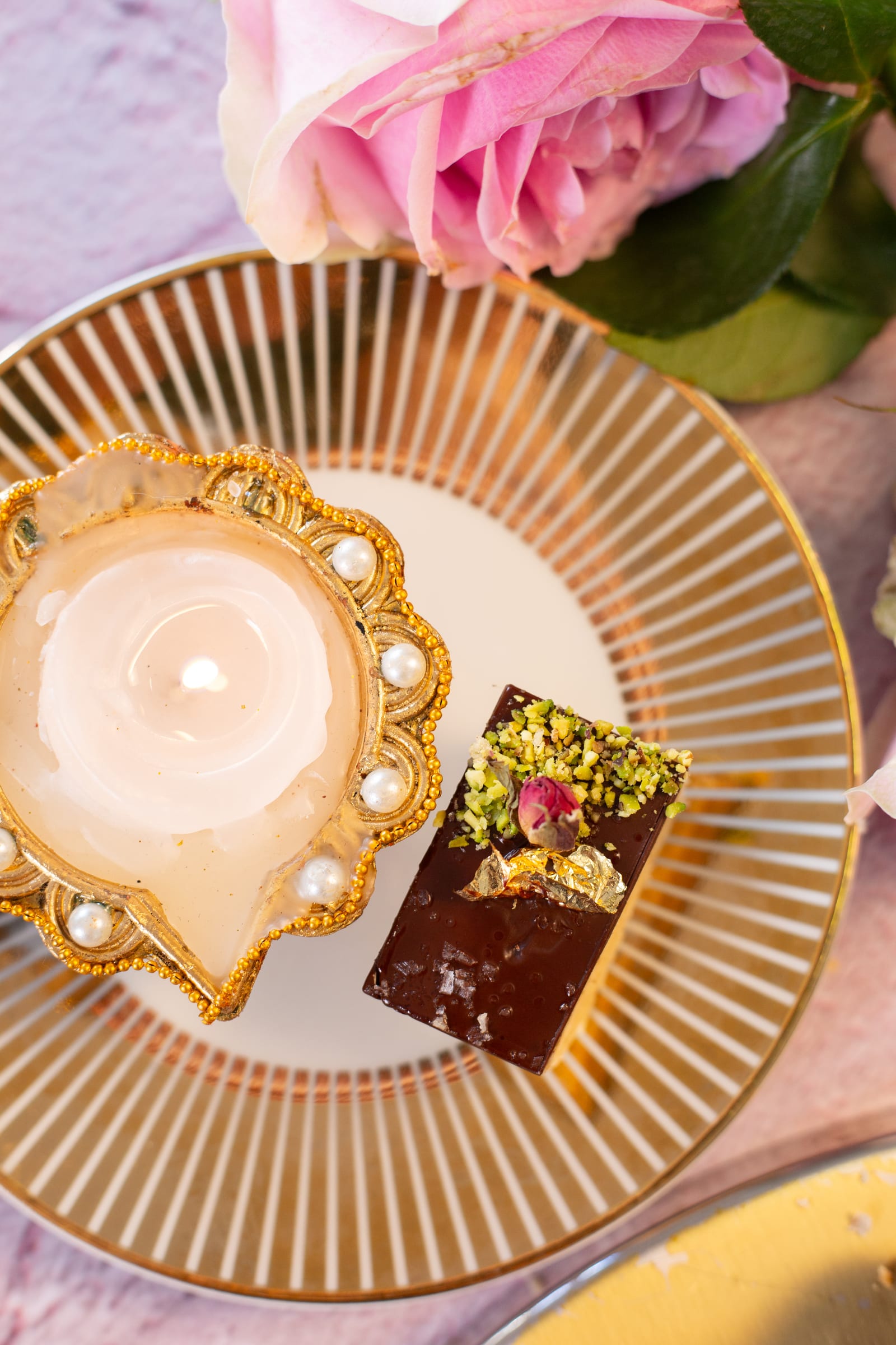 A piece of millionaire's shortbread on a gold plate beside a diya