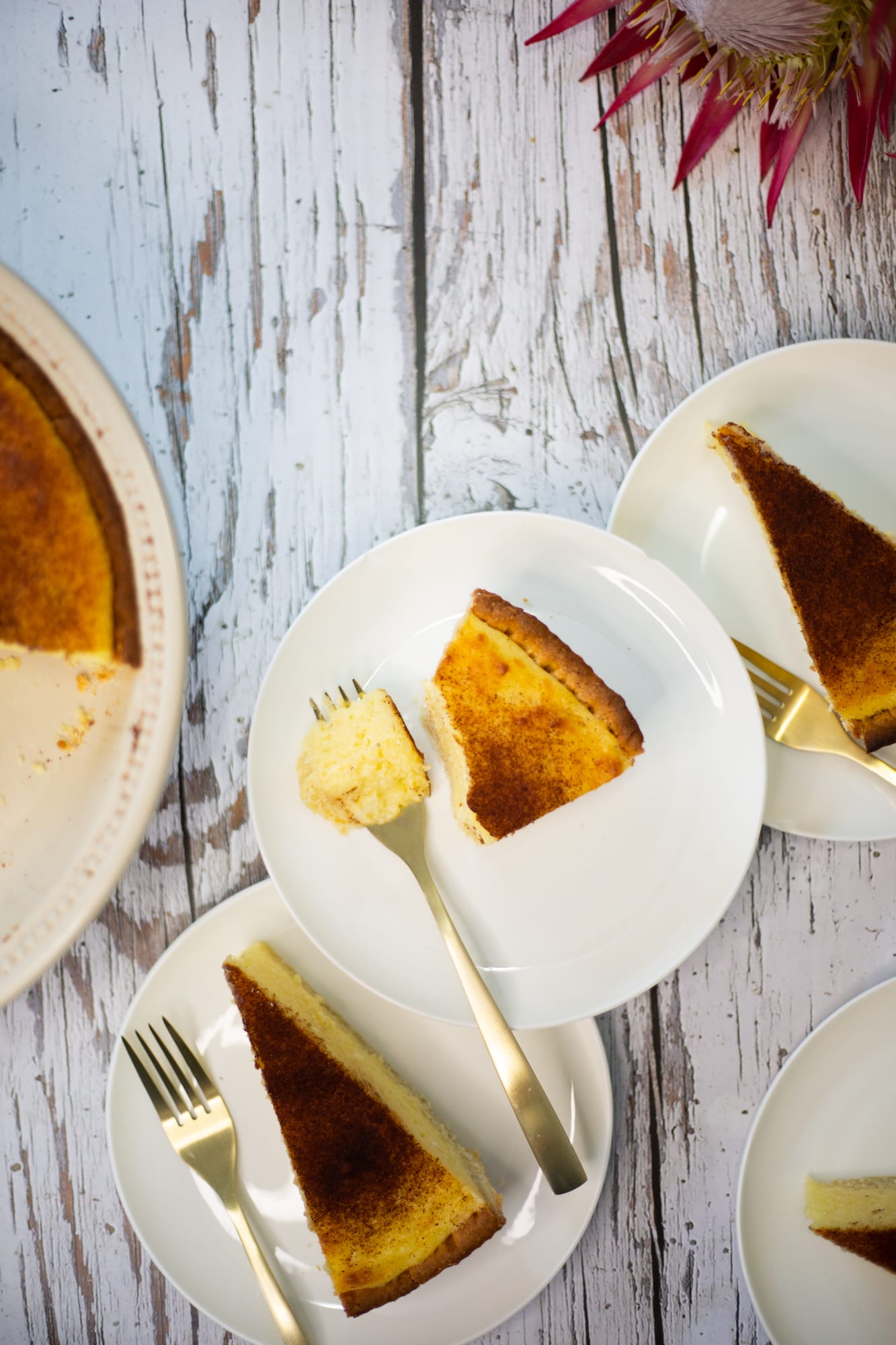Slices of melktert on plates with forks beside the tart, from above