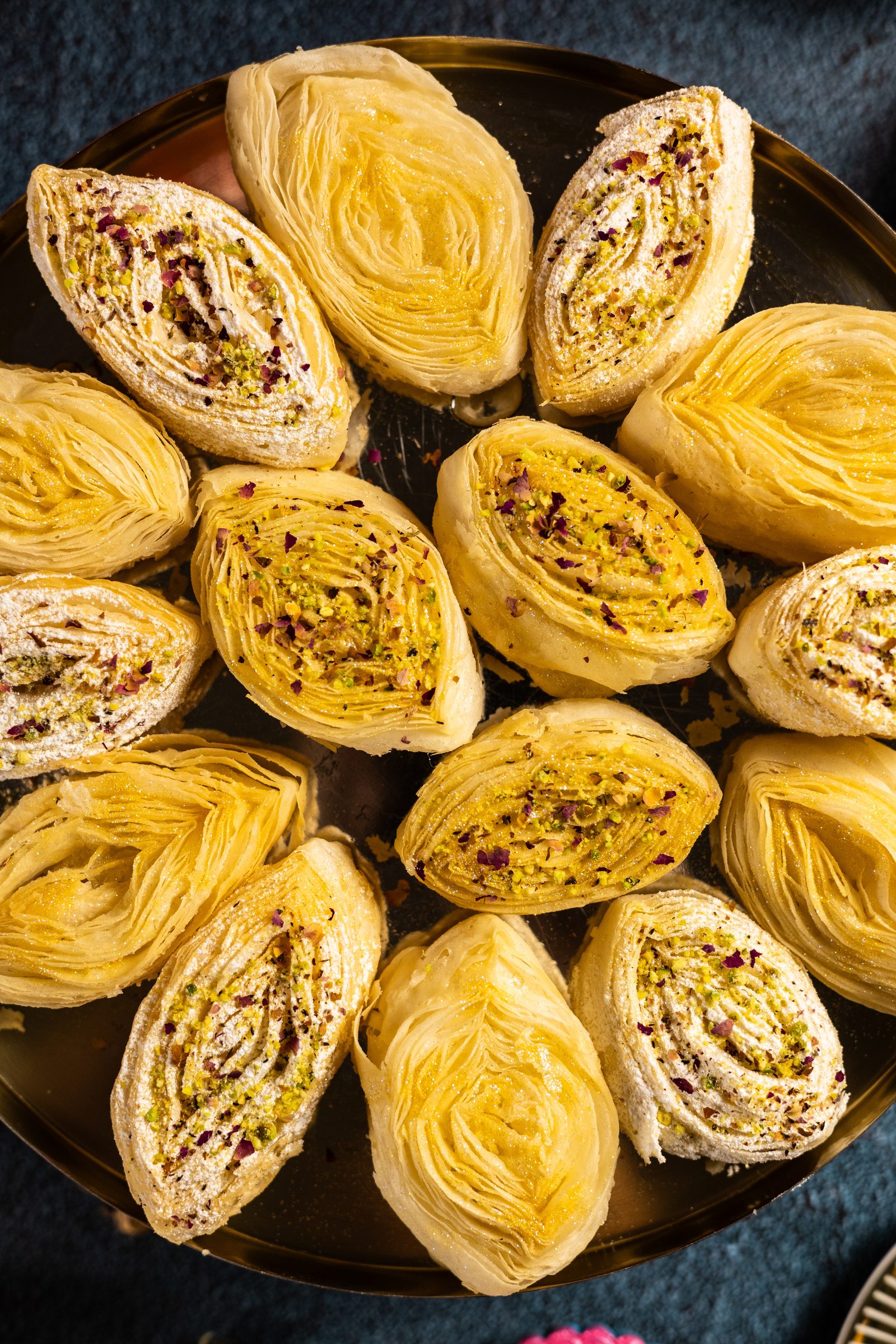 Rows of plain and sugar-dusted banana puri on a gold tray, from above