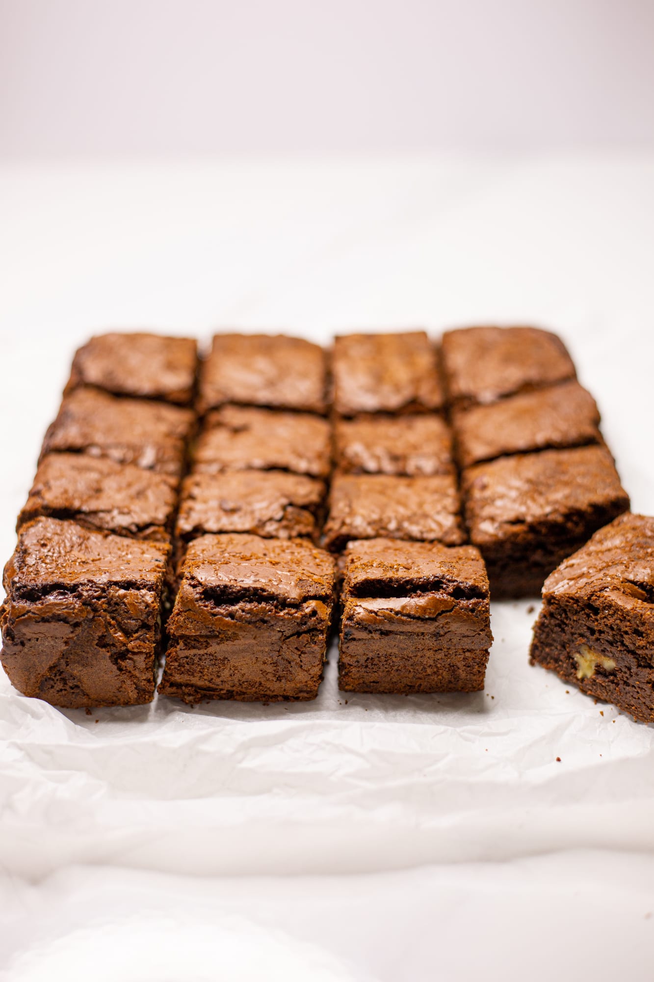 Chocolate brownies cut into squares with one pulled out, on white