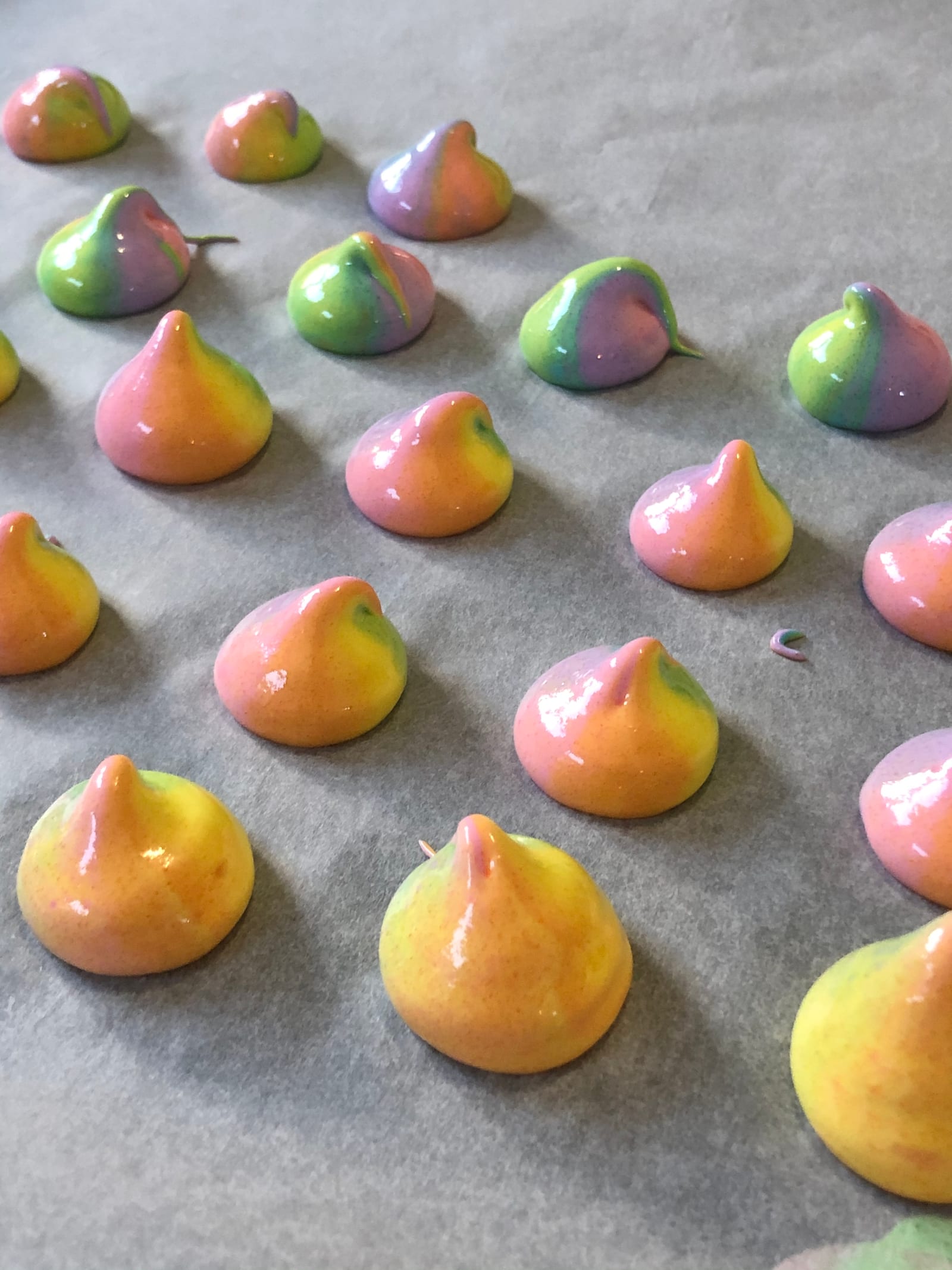 Close-up of baked rainbow meringue kisses on parchment