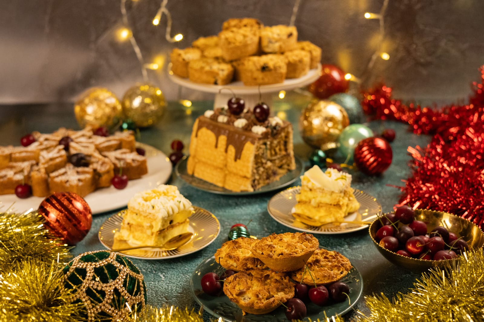 A festive spread of cakes, tarts and biscuits with Christmas baubles and fairy lights