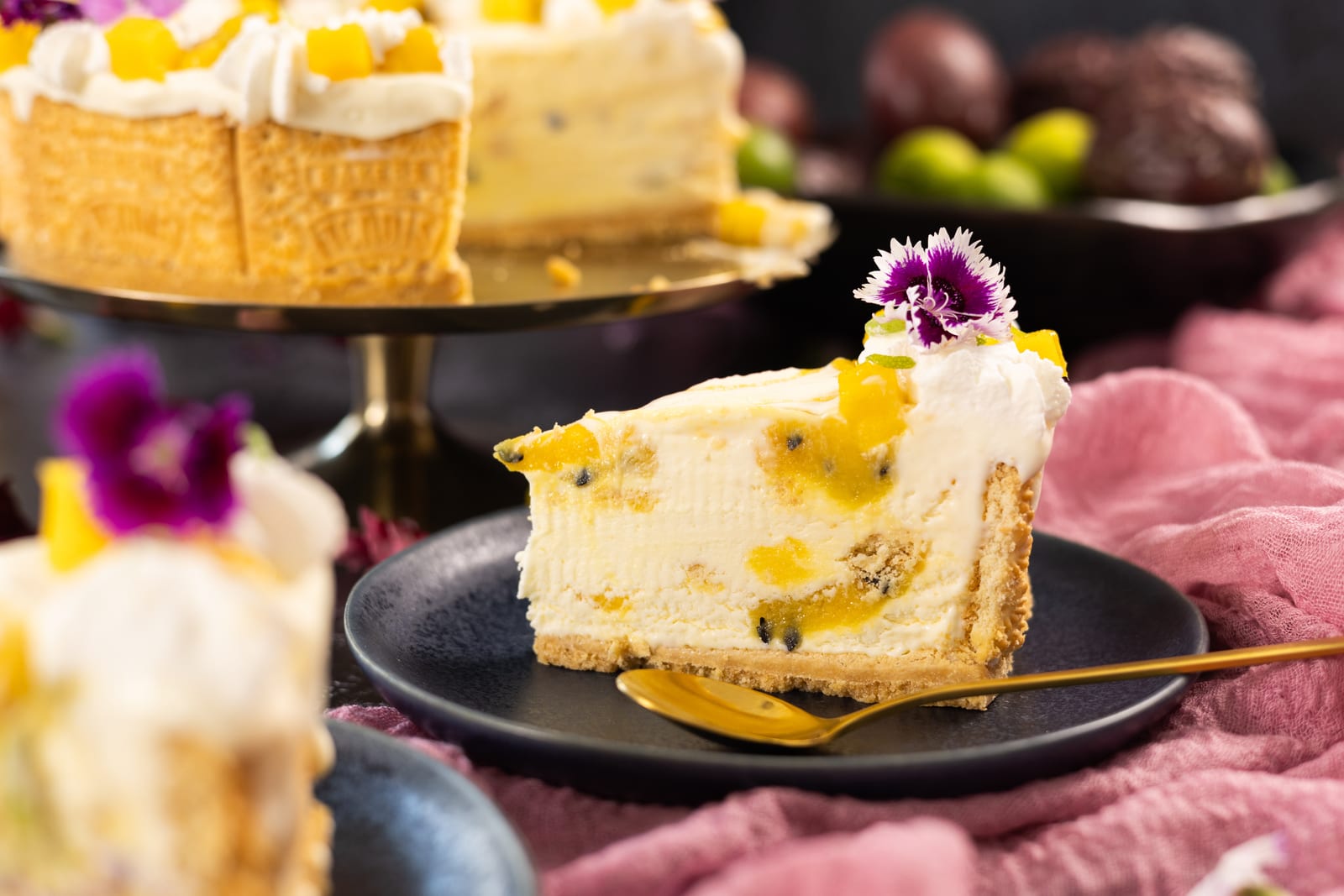 A slice of passionfruit ice cream cake on a dark plate with a gold spoon