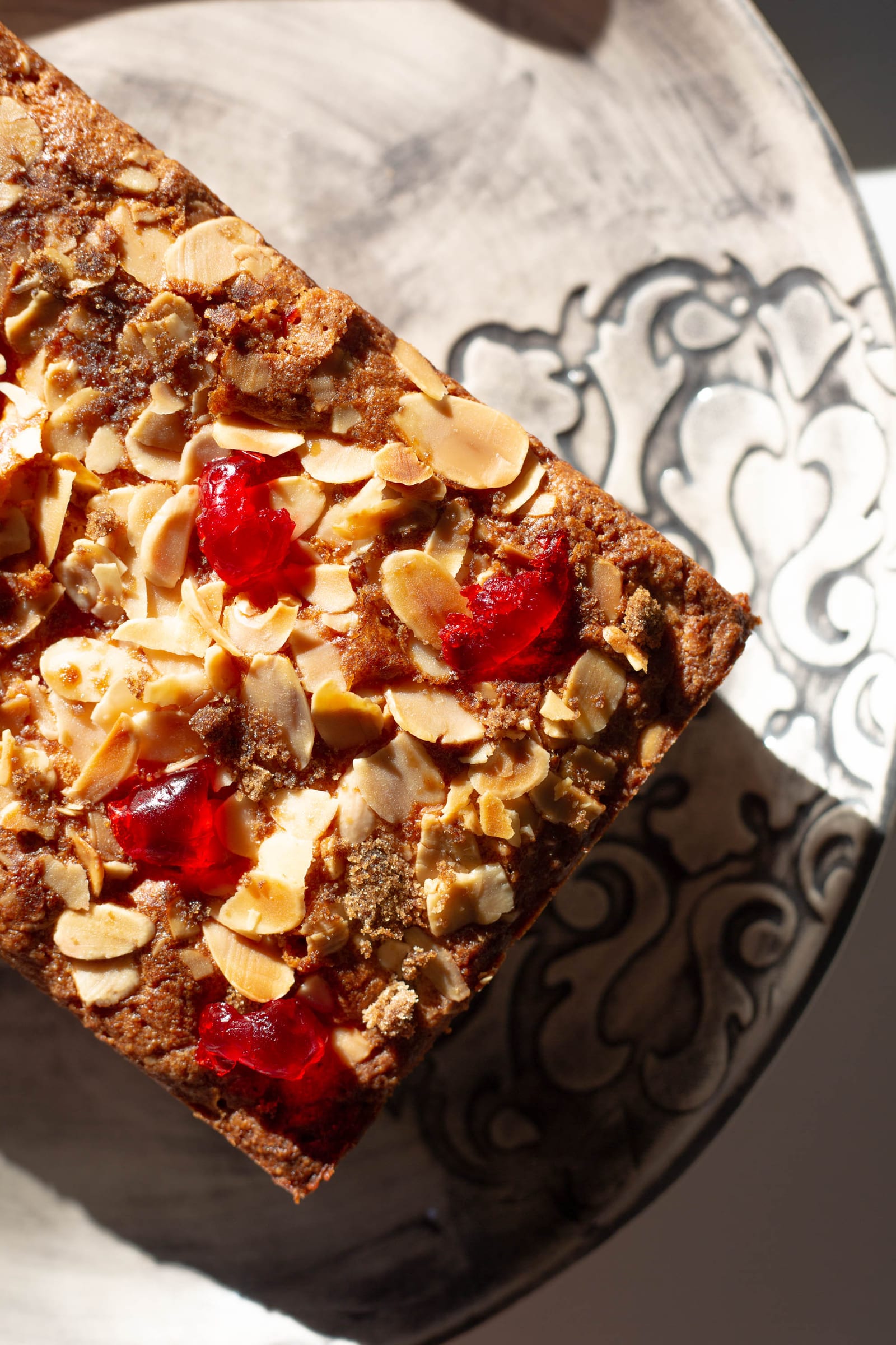 Close-up of the flaked almonds and glacé cherries on top of a gluten-free cherry and almond loaf