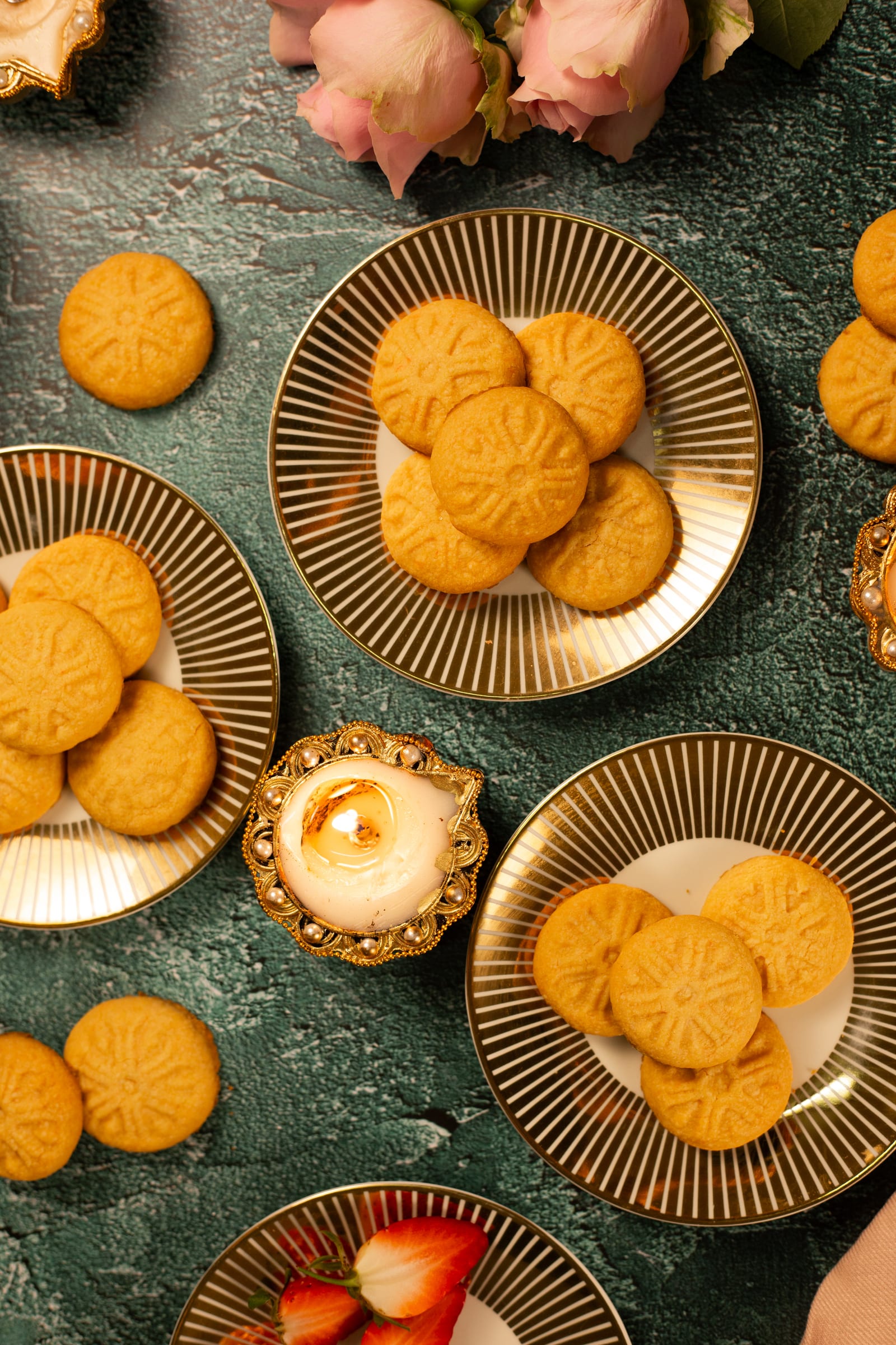 Plates of custard biscuits with diyas and roses, from above