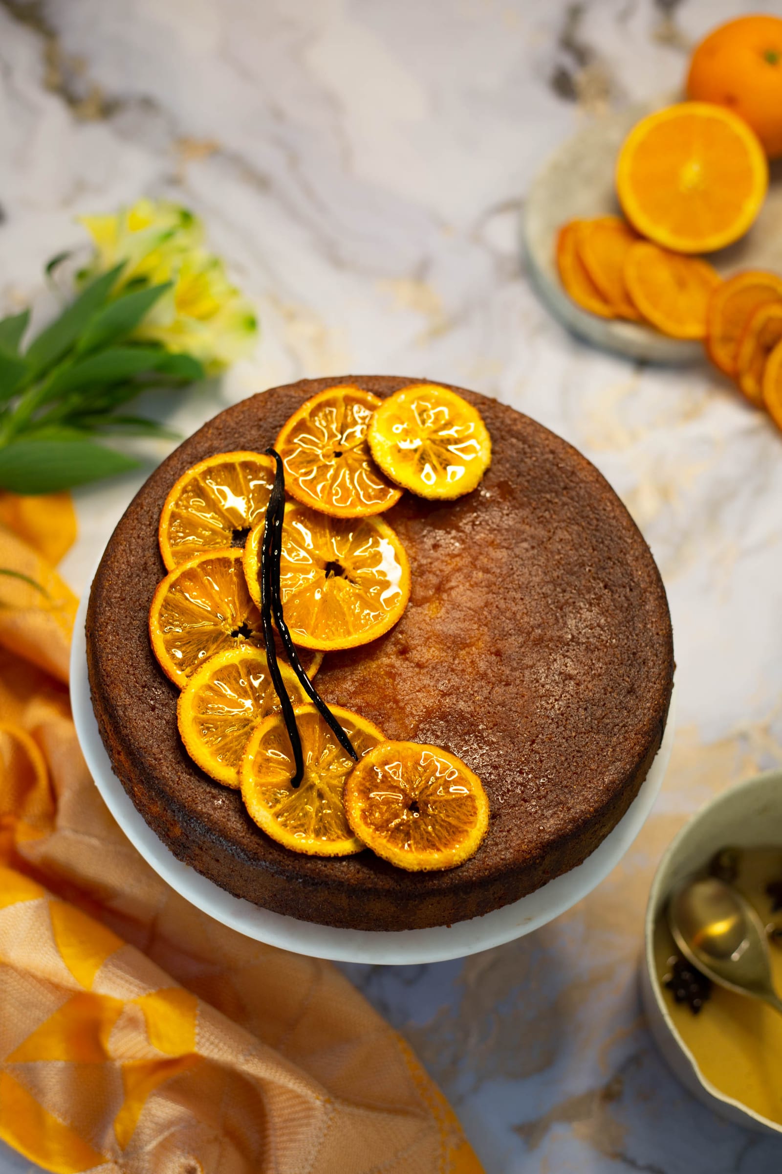 A whole orange, cardamom and polenta cake topped with candied orange slices and a vanilla pod, from above