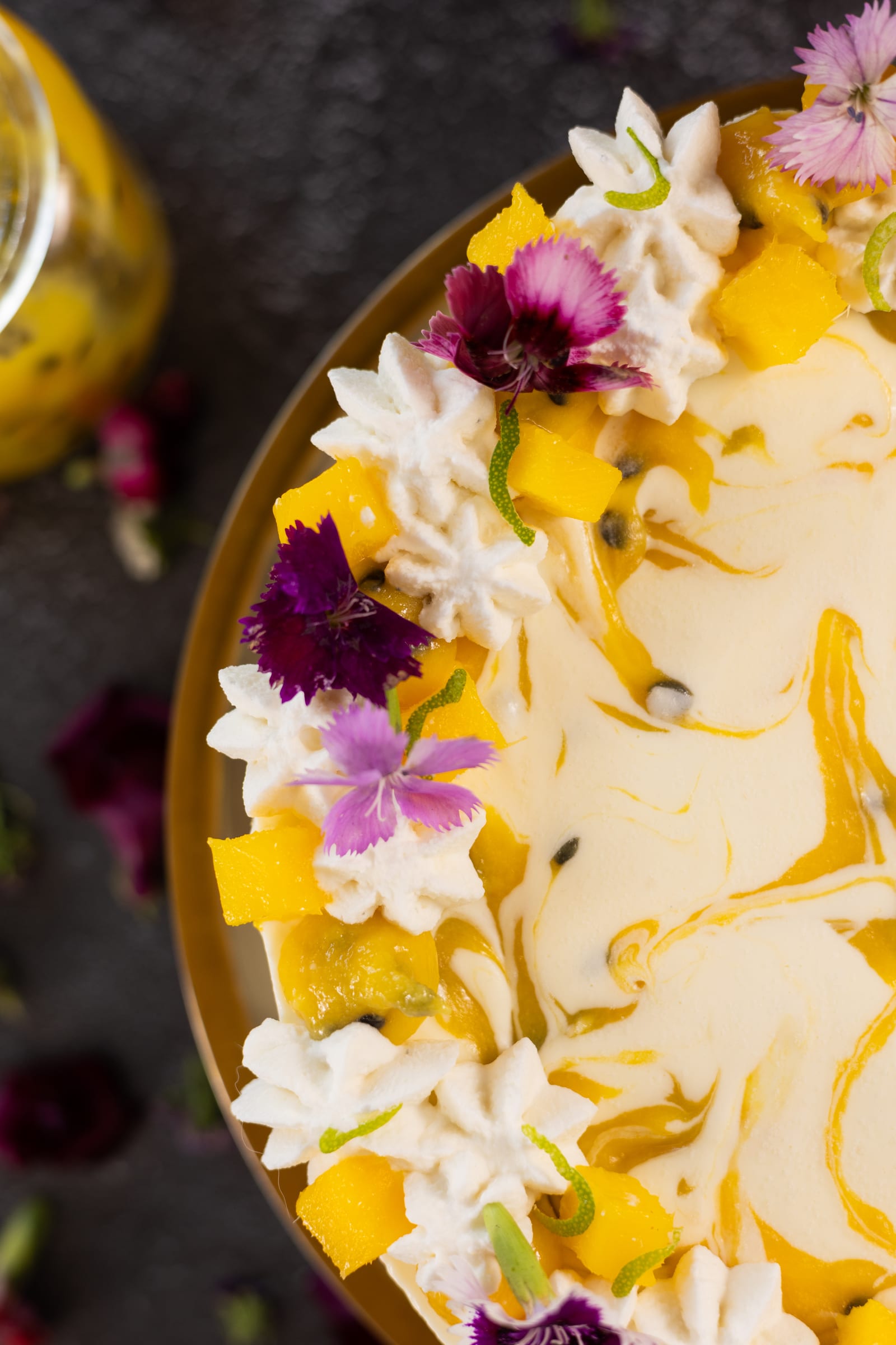 Close-up of edible flowers and mango on the ice cream cake