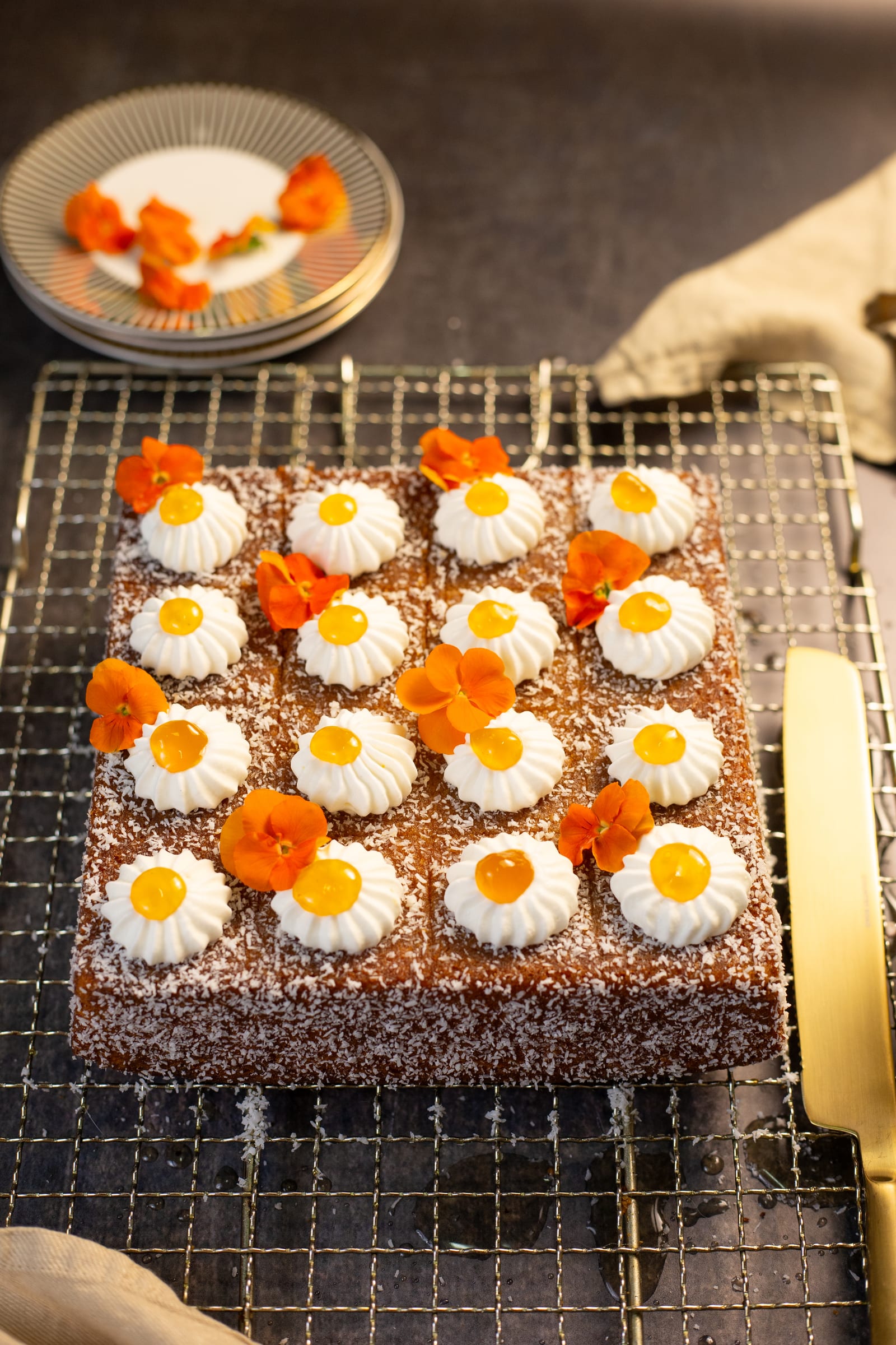 The whole koesister traybake on a cooling rack, decorated with cream and orange flowers