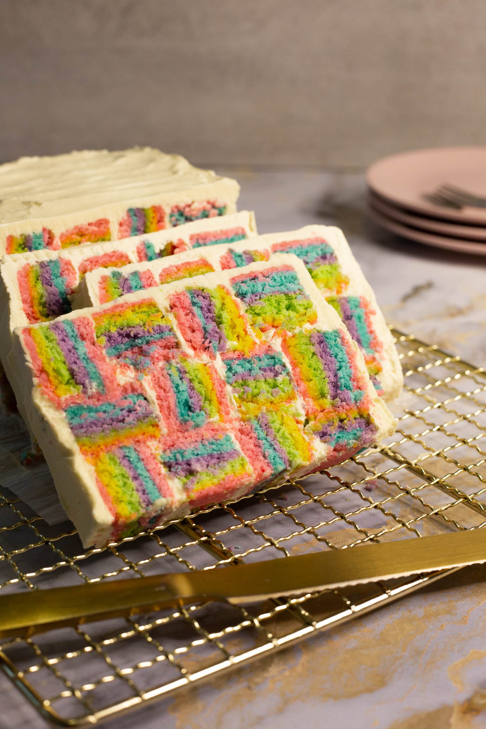Slices of rainbow coconut layer cake fanned out on a gold rack