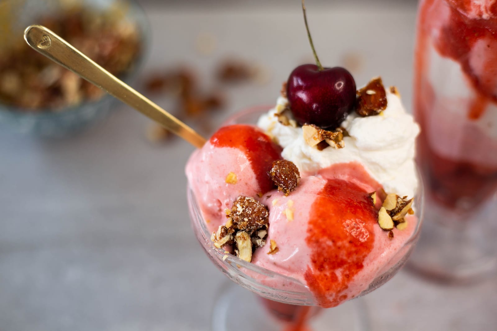 The top of a berries and cream sundae: cherry, chantilly cream, candied almonds and raspberry sauce