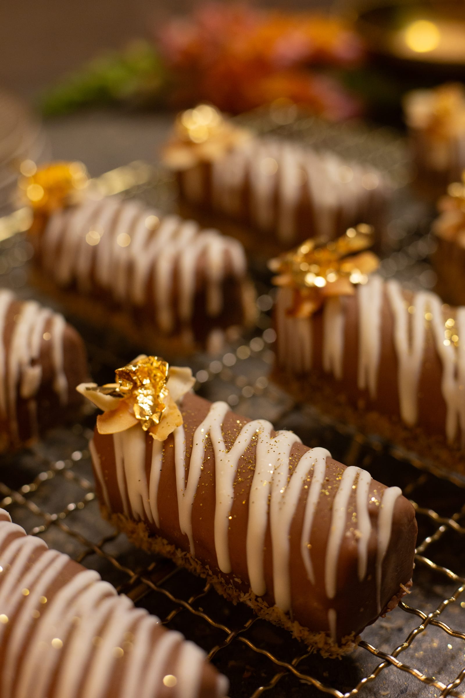 A coconut, caramel and chocolate log topped with gold leaf and a white chocolate drizzle