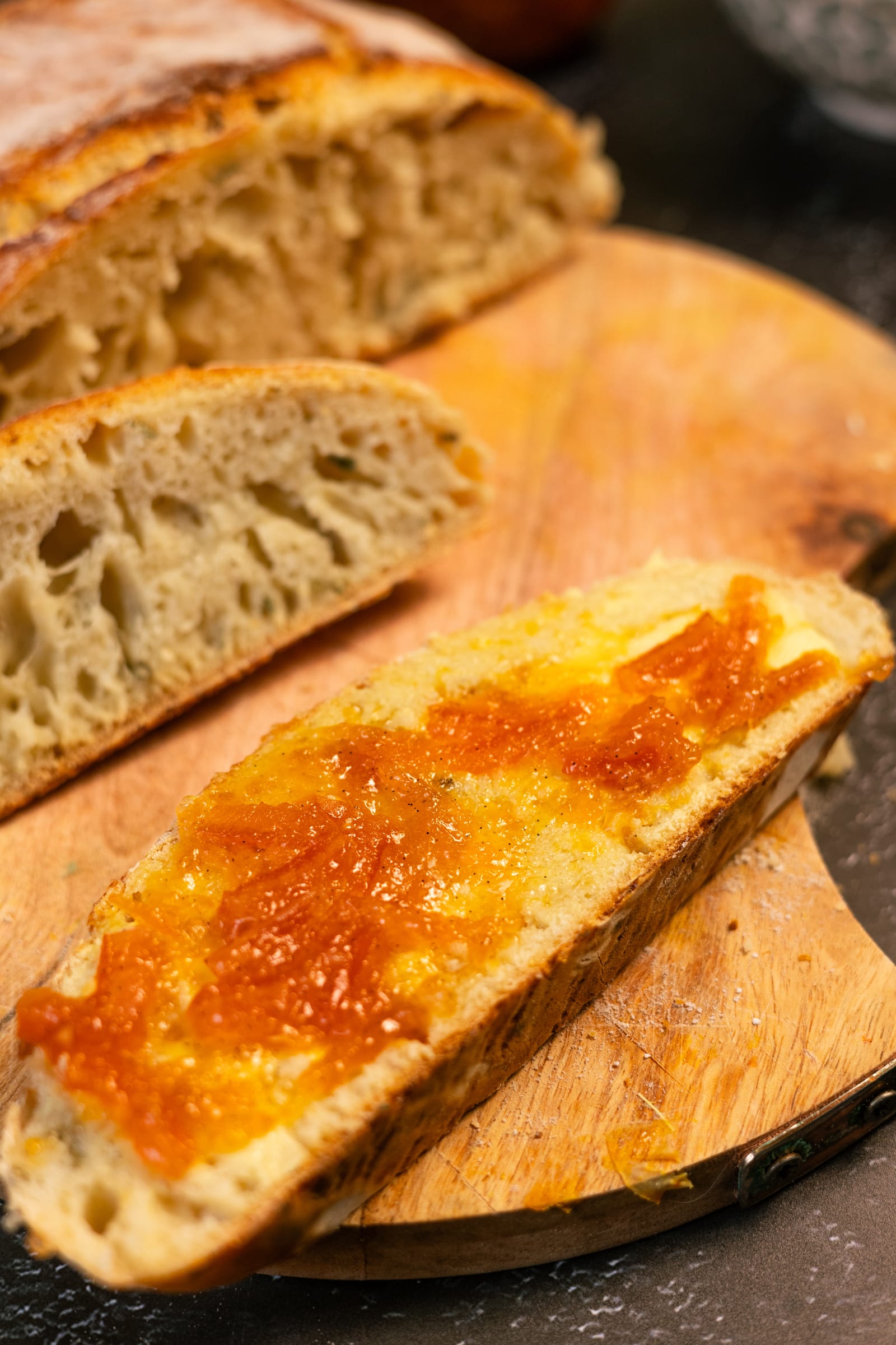 A thick slice of bread with marmalade, next to the loaf