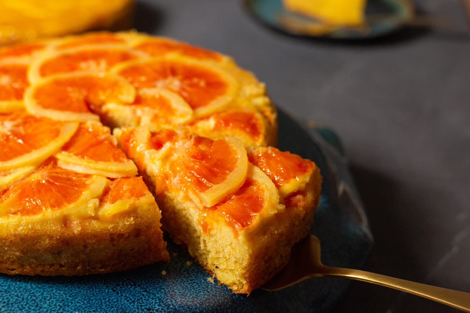 A slice being lifted out of an orange upside down cake on a cake server