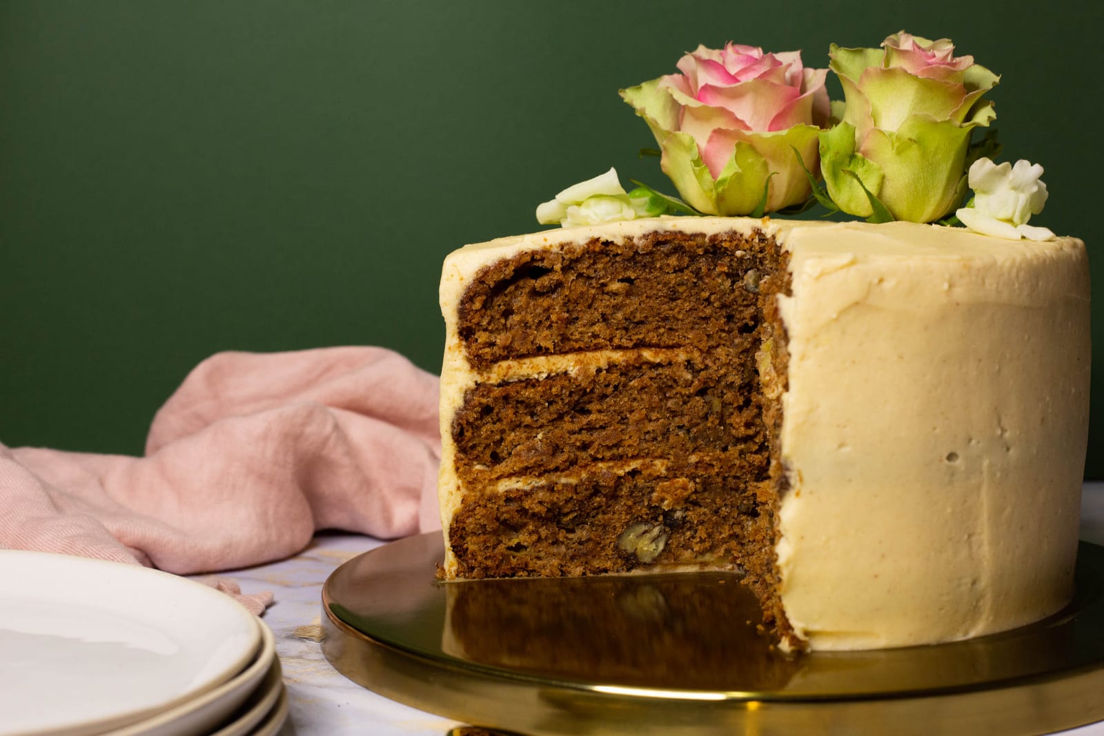 A hummingbird cake with brown butter cream cheese frosting cut open to show its three layers, plates beside it