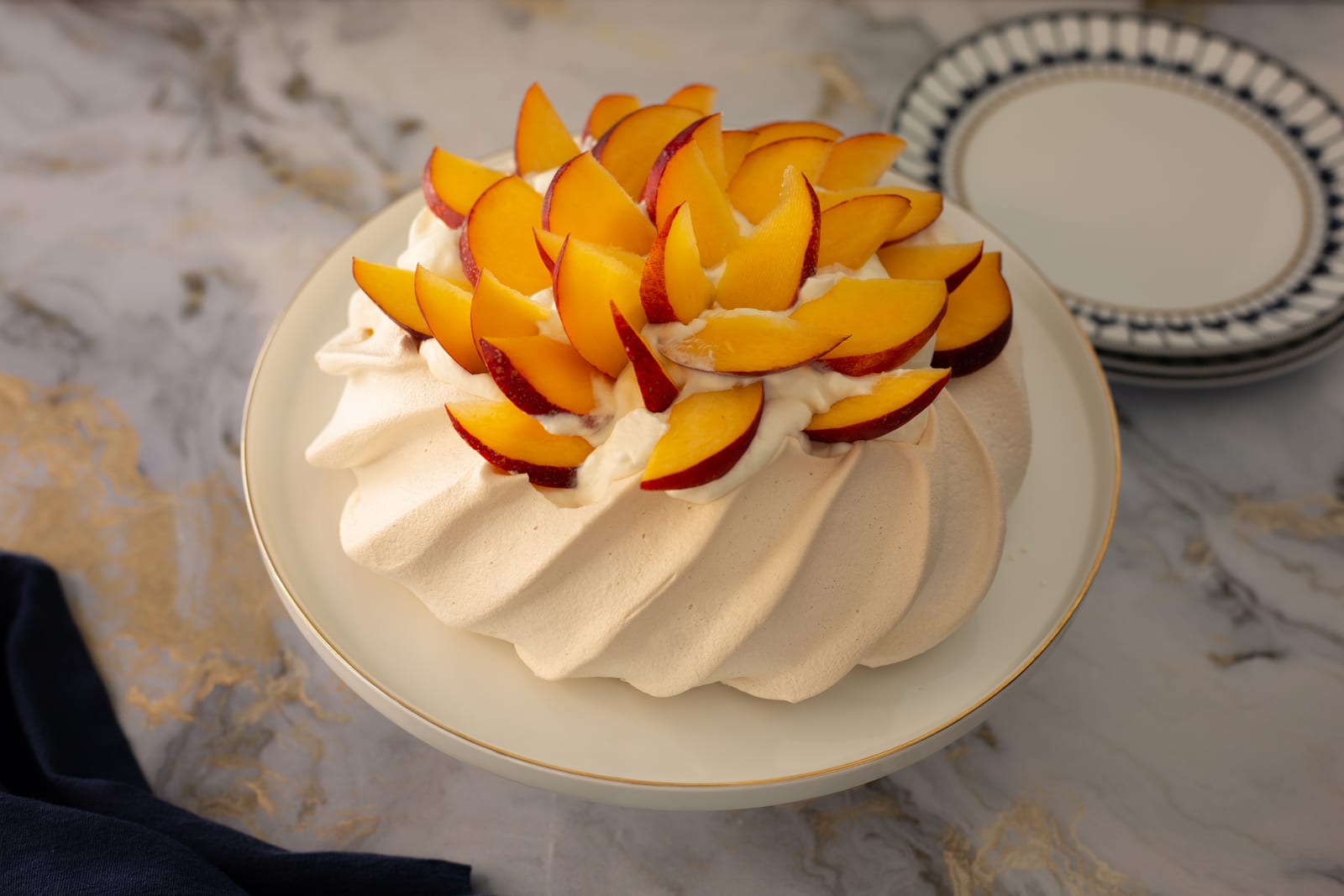 The meringue topped with whipped cream and fanned nectarine slices