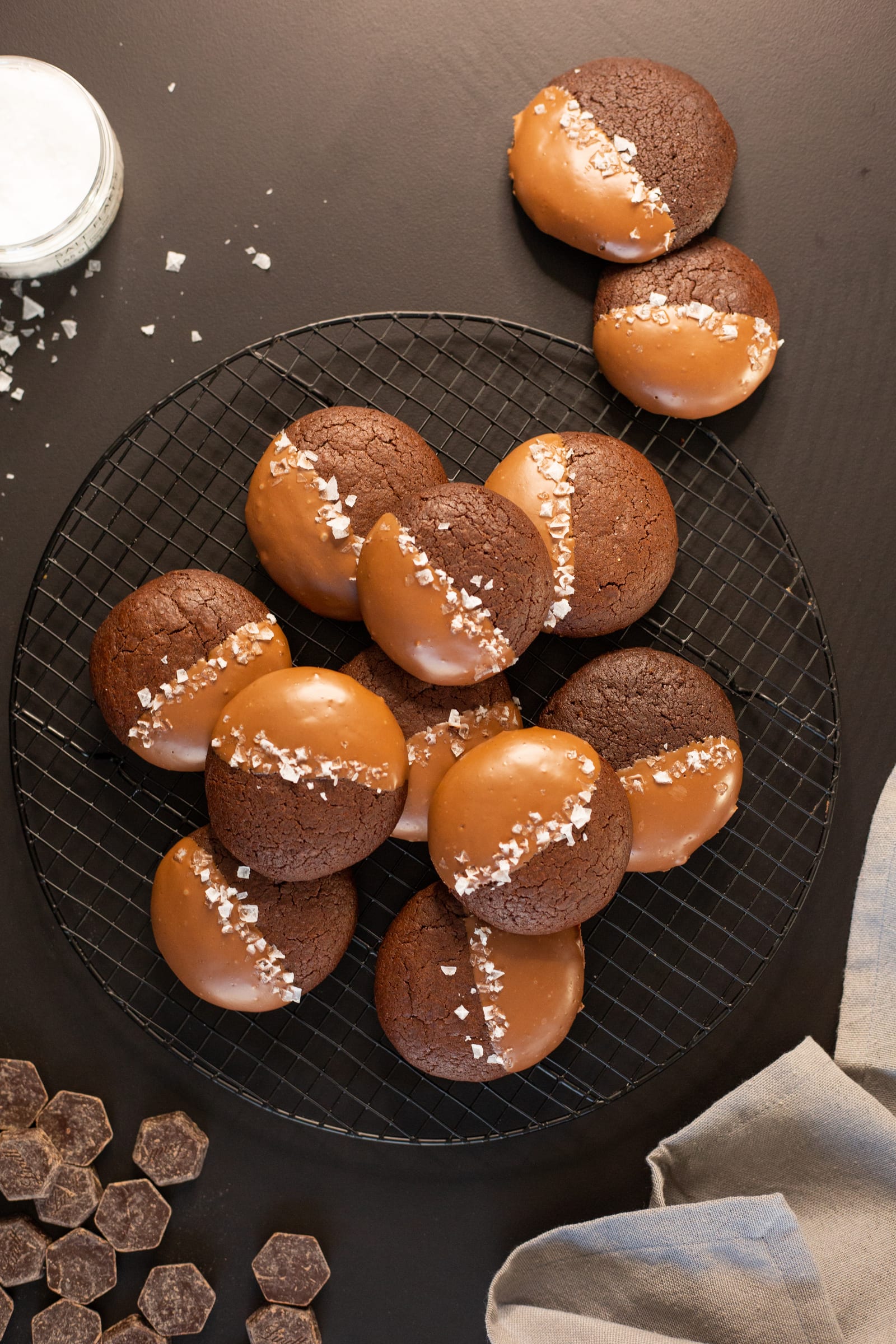 A wire rack of rye brownie cookies half-dipped in milk chocolate, from above