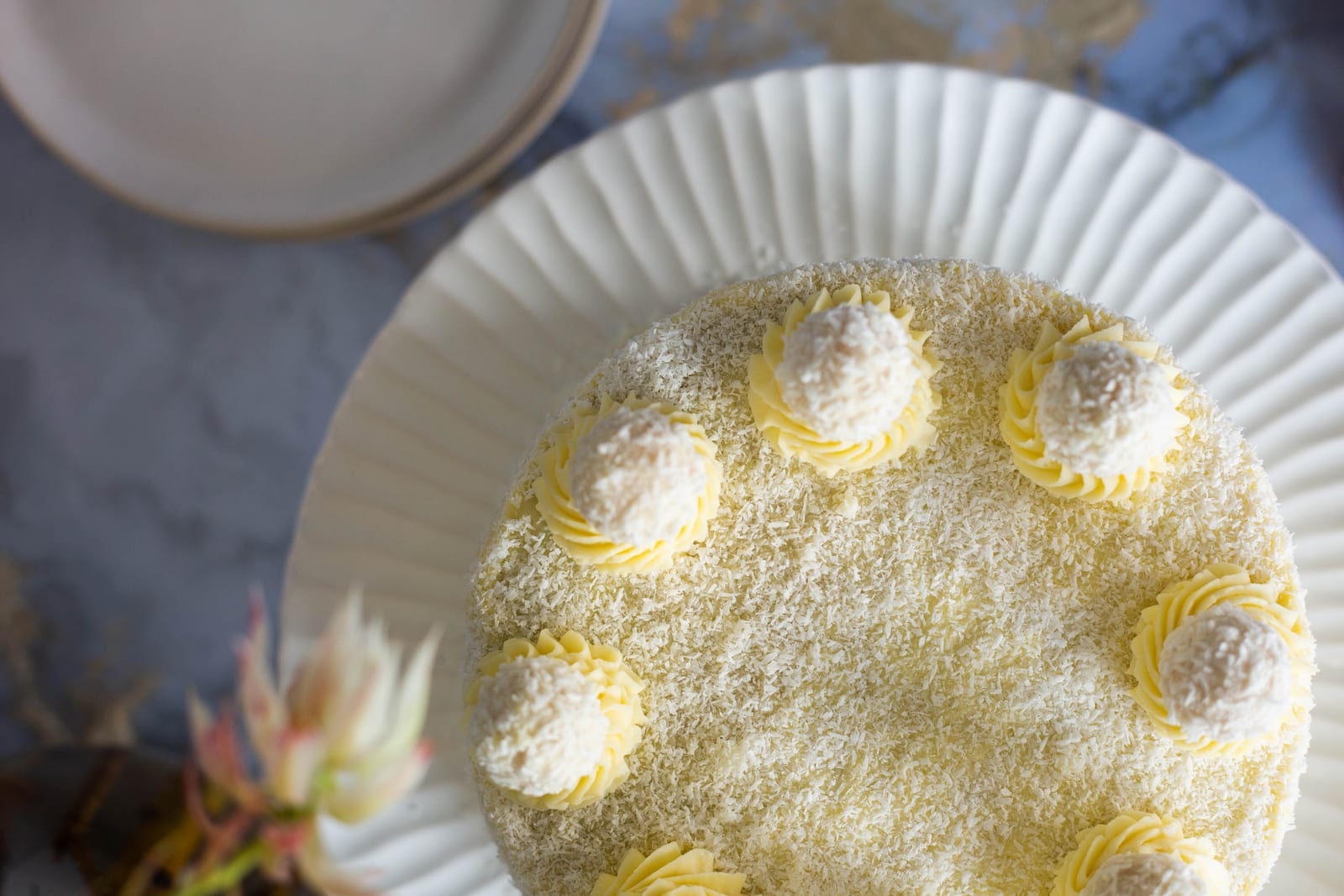 The top of a whole Raffaello cake, with piped rosettes and coconut balls, from above