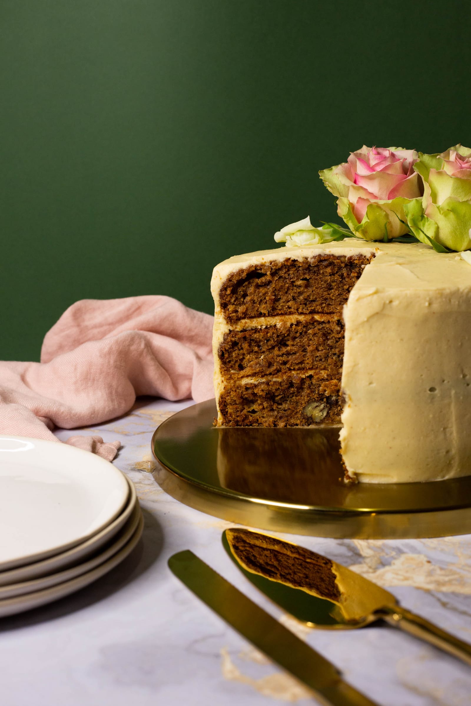 A cut hummingbird cake with a slice on a gold server and plates in front