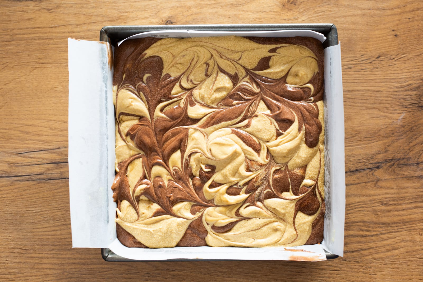 Chocolate and caramel cake batters swirled together in the tin