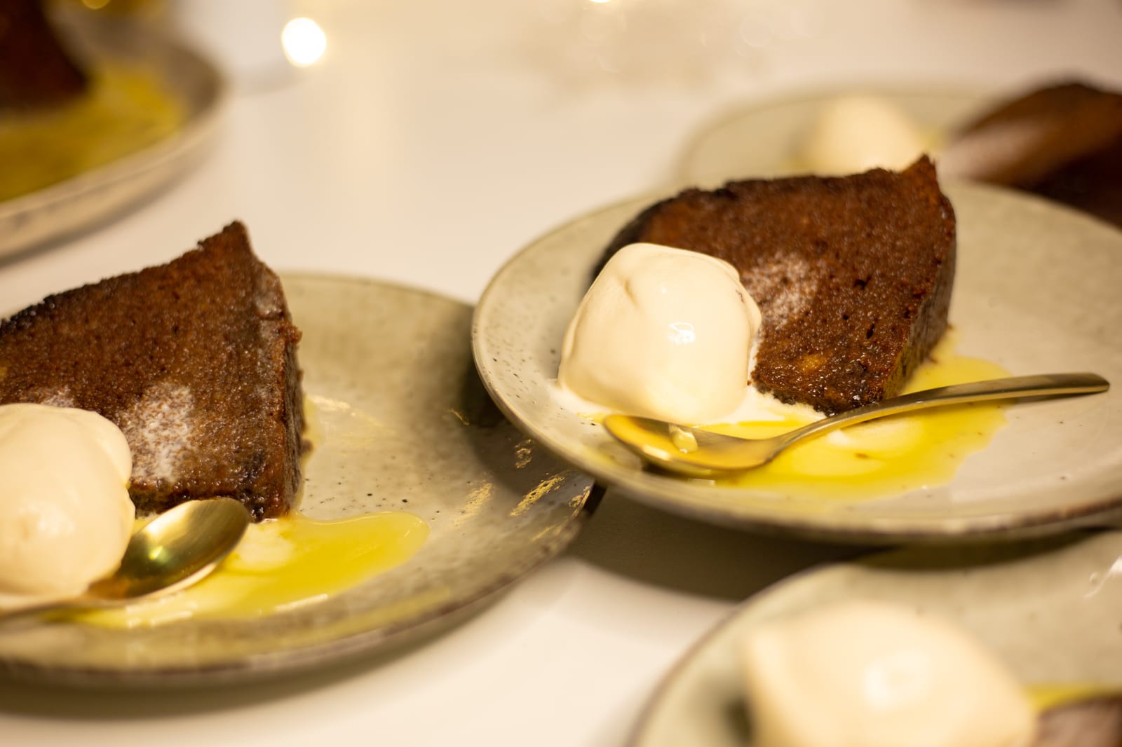 Slices of gingerbread pudding with ice cream and sauce on plates