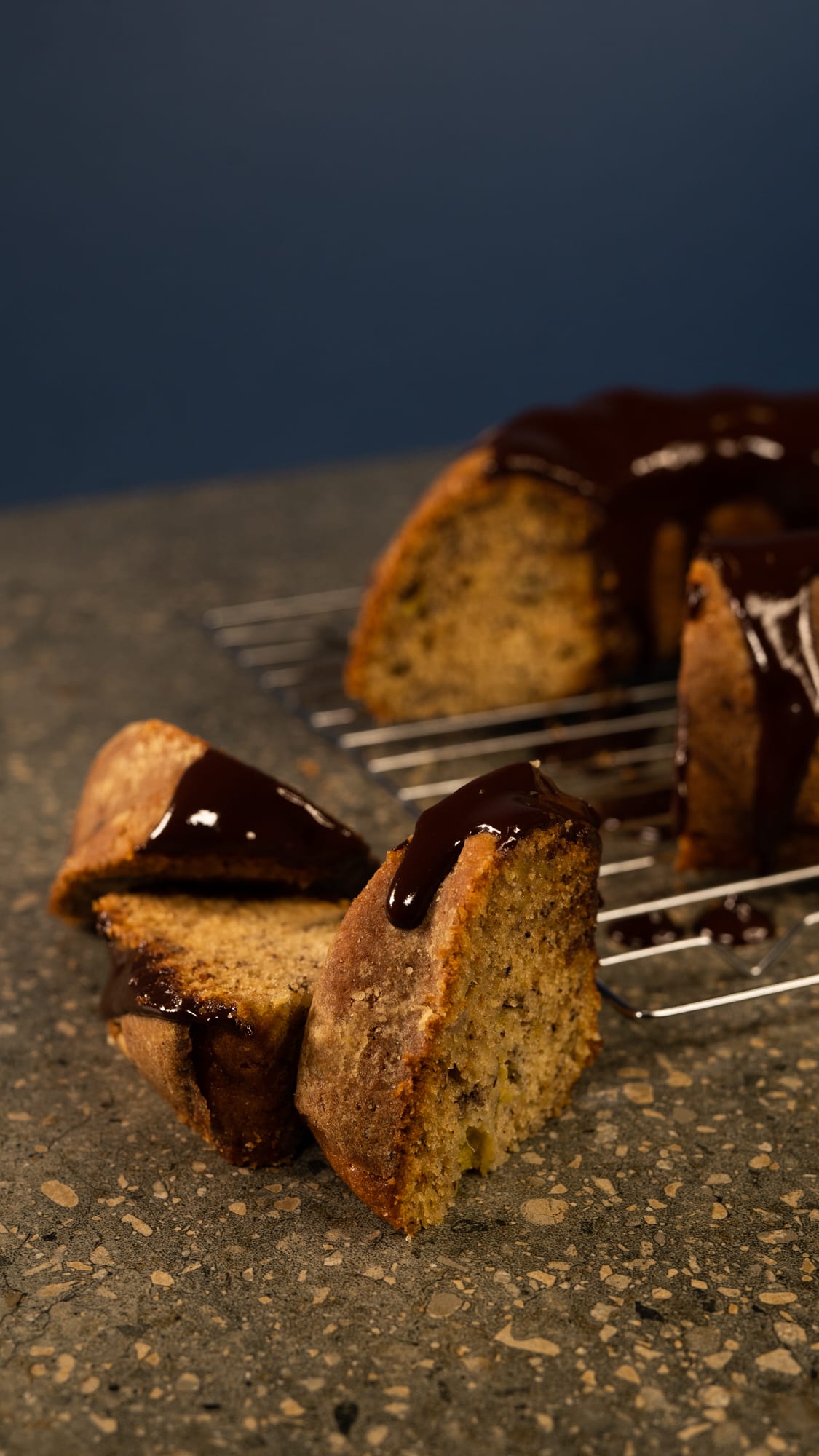 Slices of banana cake with ganache in front of the rest of the cake