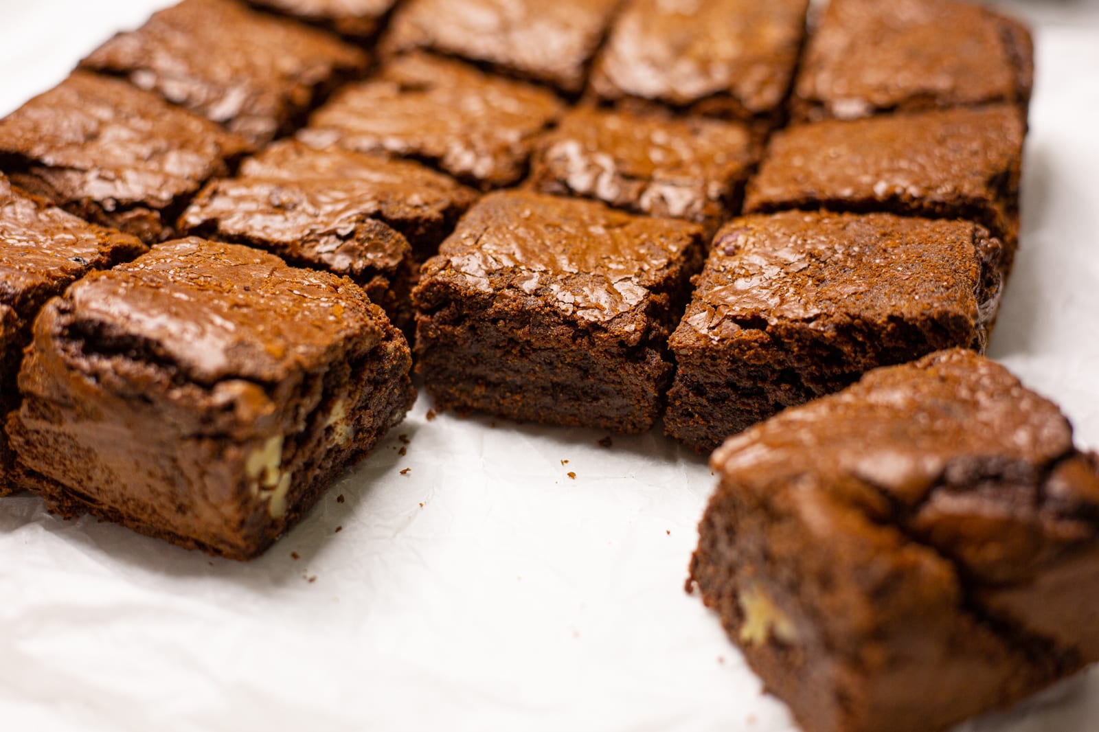 A chocolate brownie pulled out of the batch, showing its crackly top and walnuts