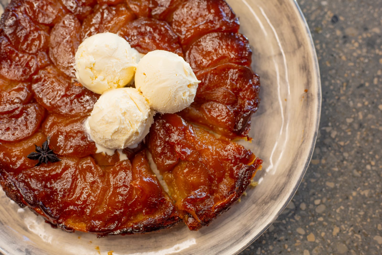 An apple tarte tatin topped with vanilla ice cream, a wedge cut, from above