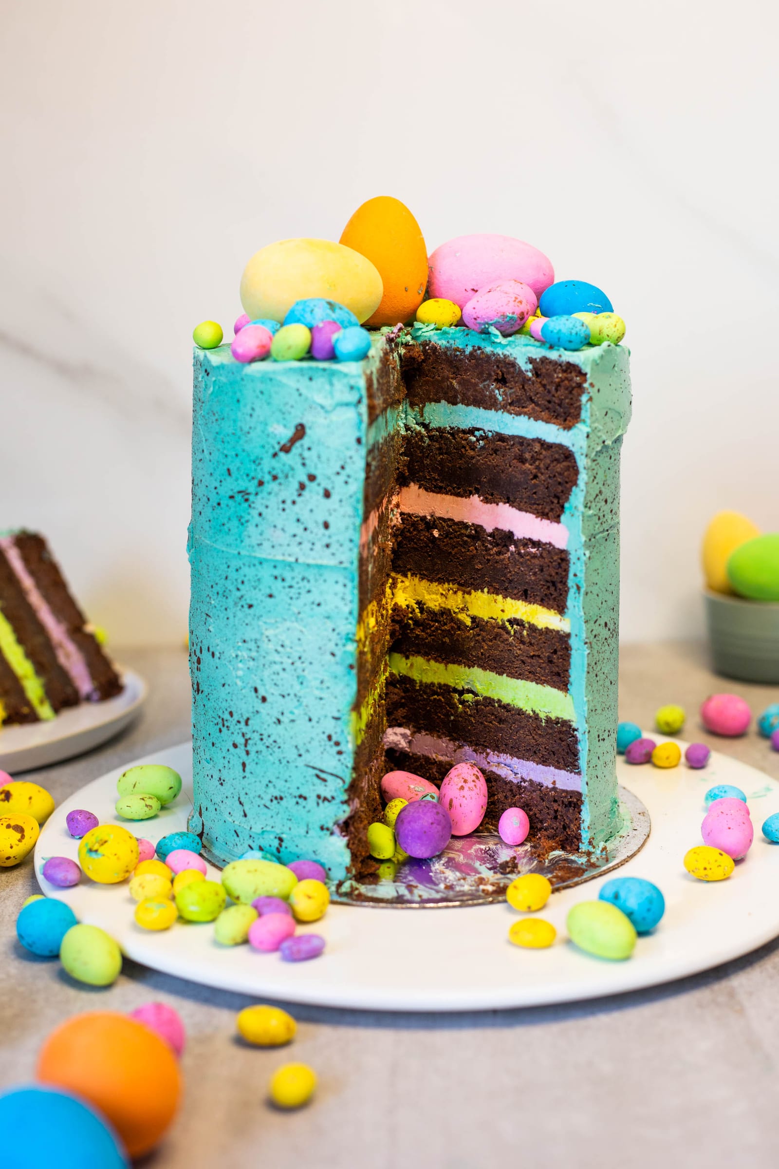 A cut speckled egg cake with a slice on a plate behind it