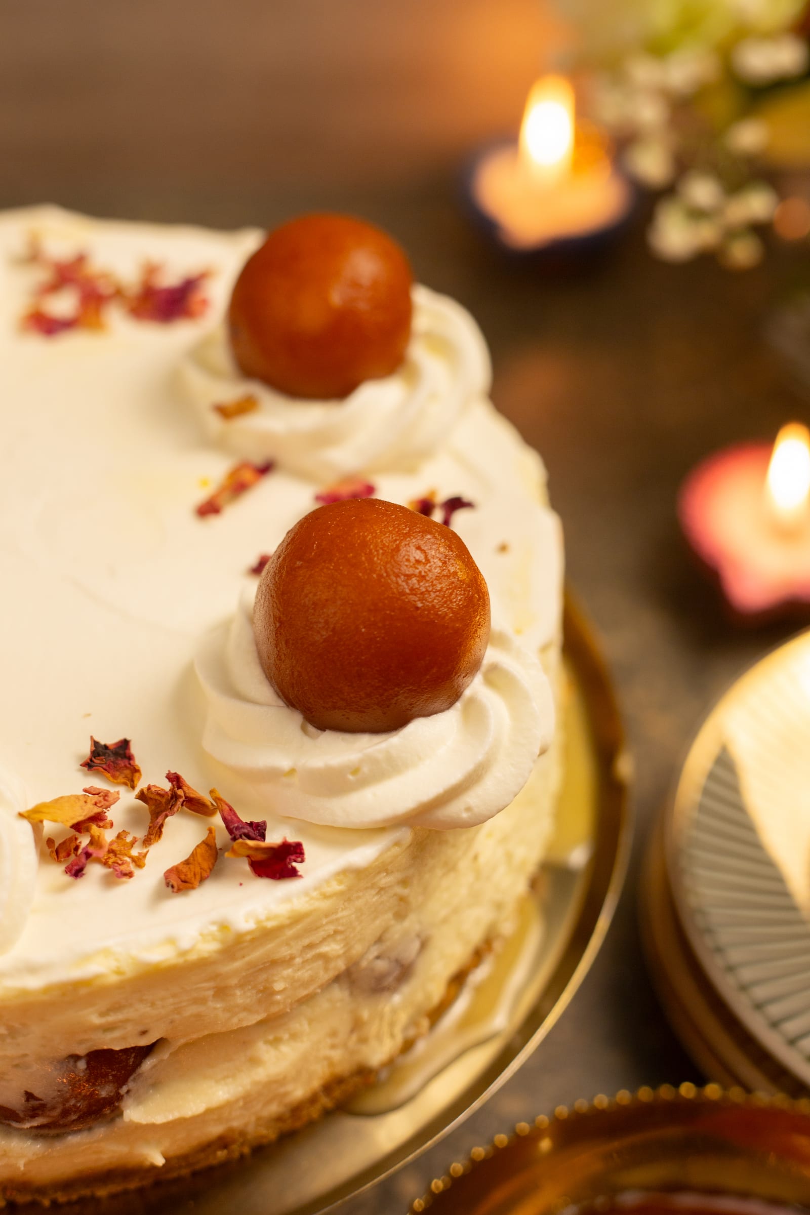 Close-up of gulab jamun and rose petals on the cheesecake