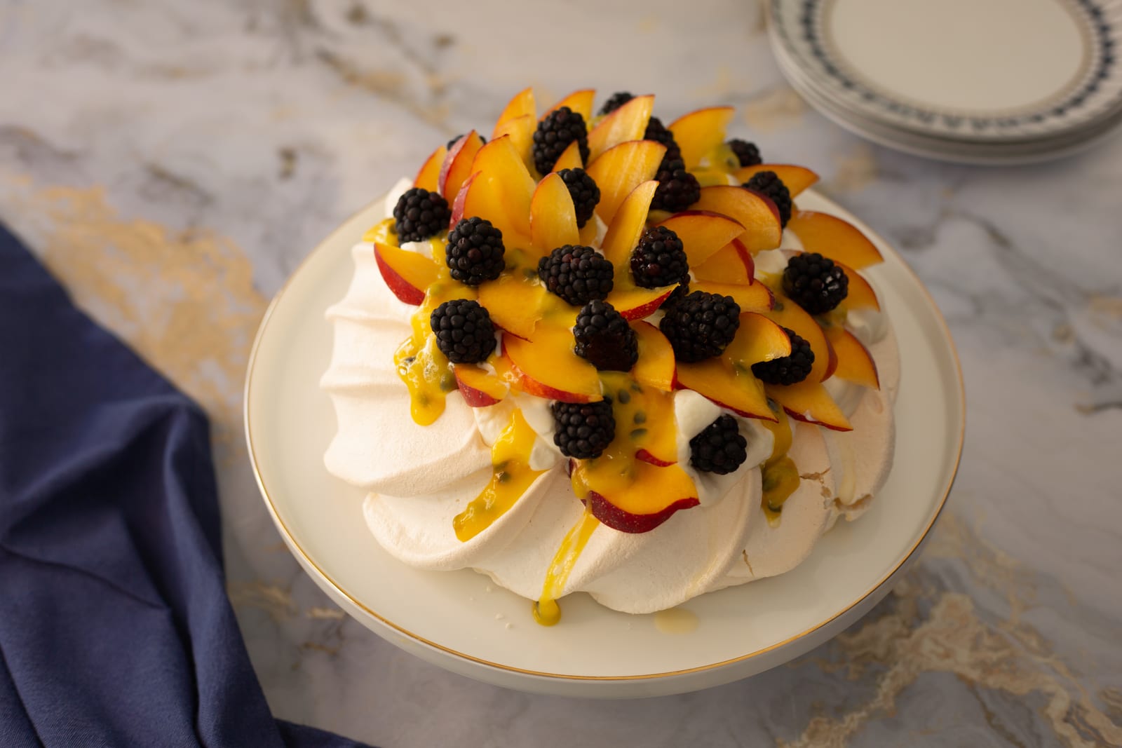 A blackberry and nectarine pavlova from above, piled with fanned nectarine slices and blackberries