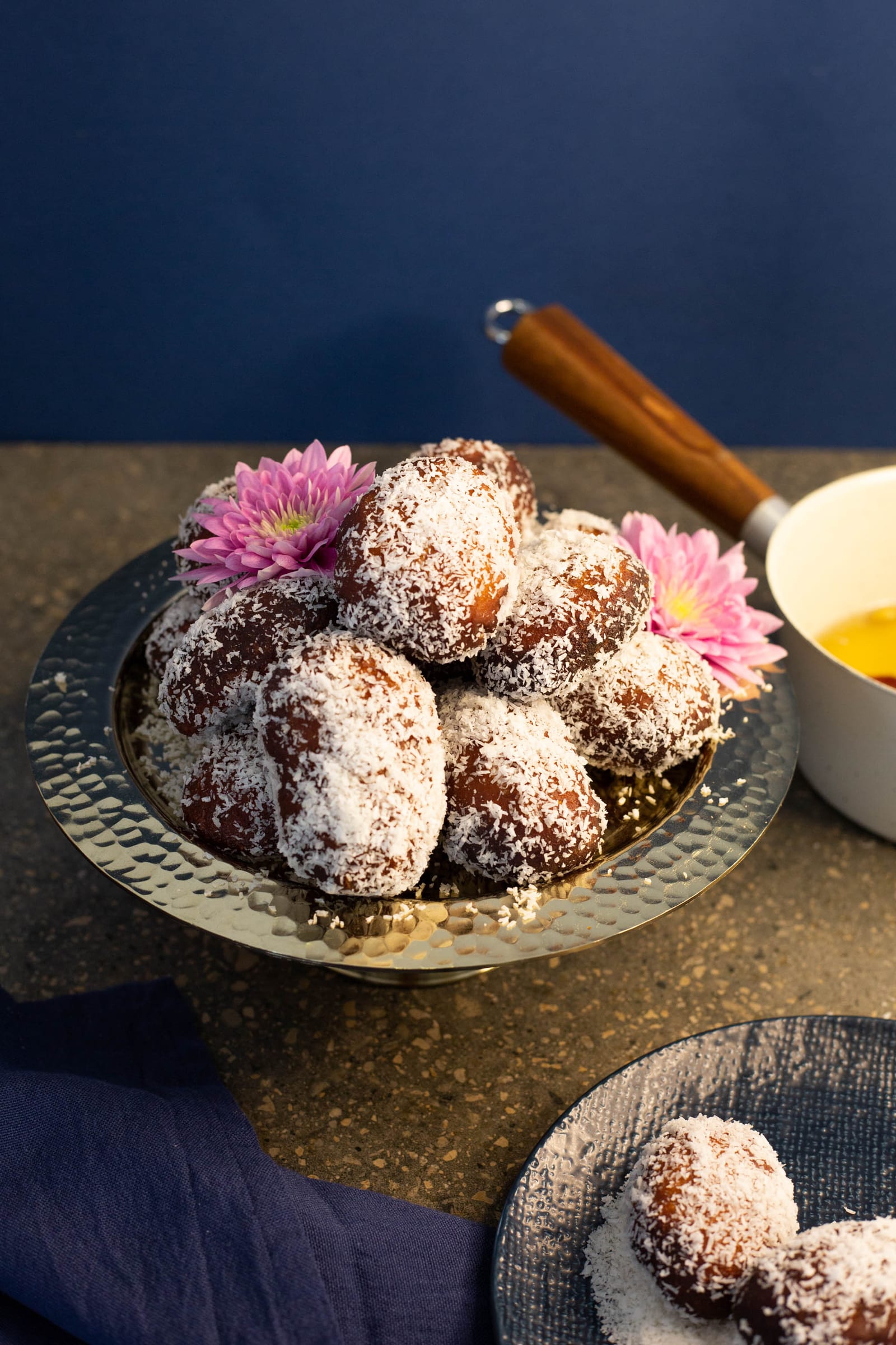 Cape Malay koesisters in a brass bowl beside a saucepan of syrup