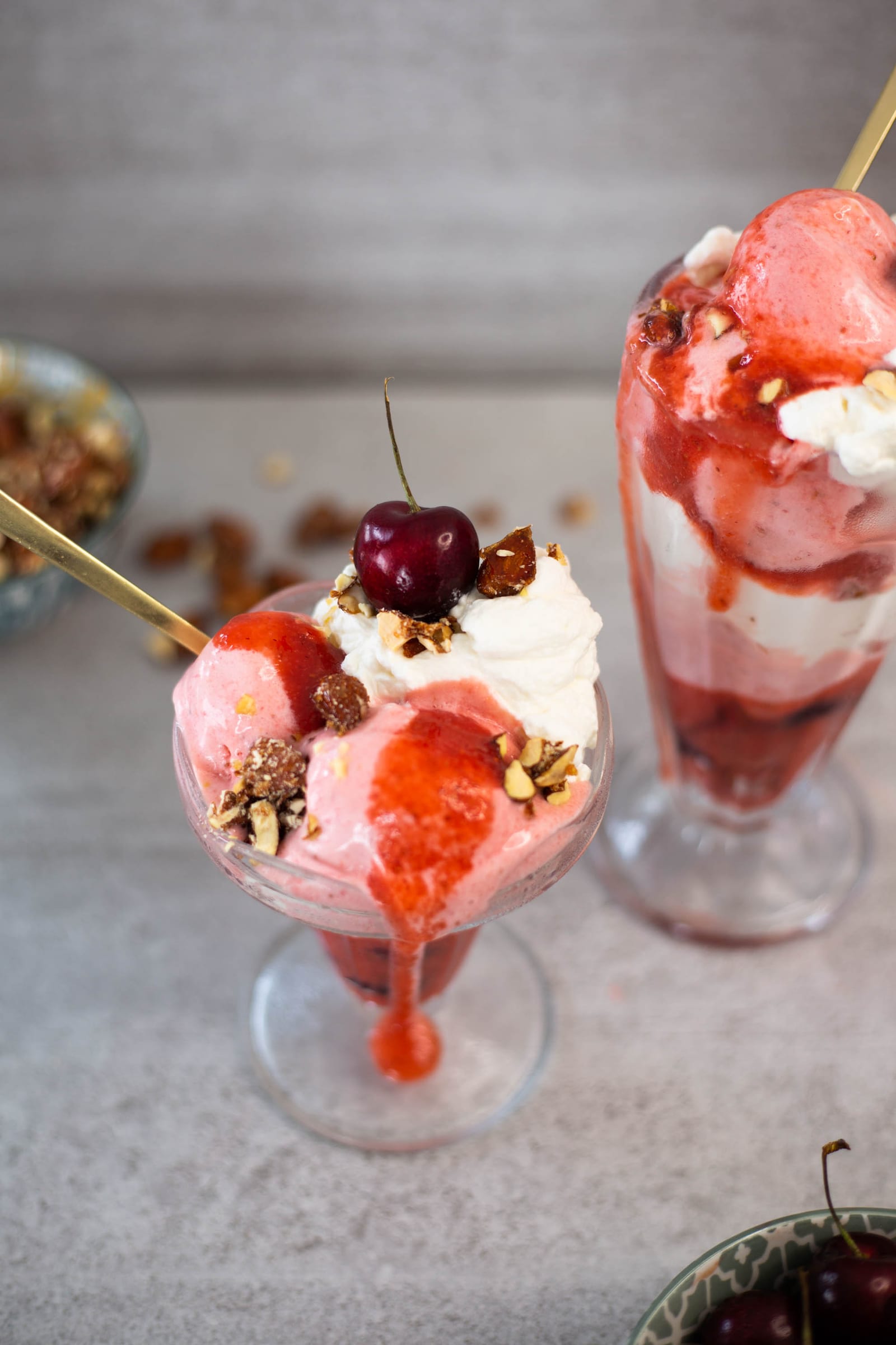 Raspberry sauce dripping down the stem of a berries and cream sundae