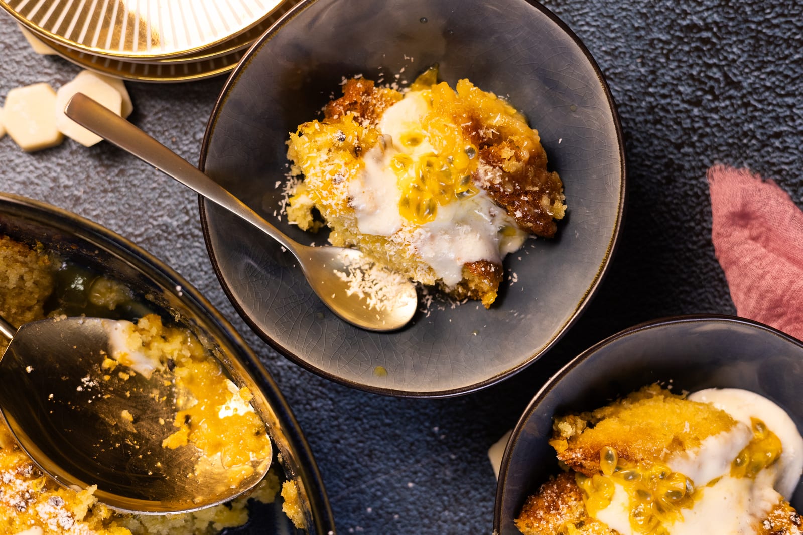 Bowls of passionfruit and coconut self-saucing pudding with coconut cream, from above