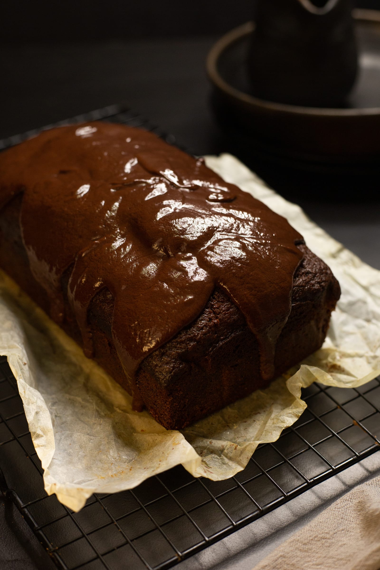 Glossy ganache running down the sides of the chocolate banana bread