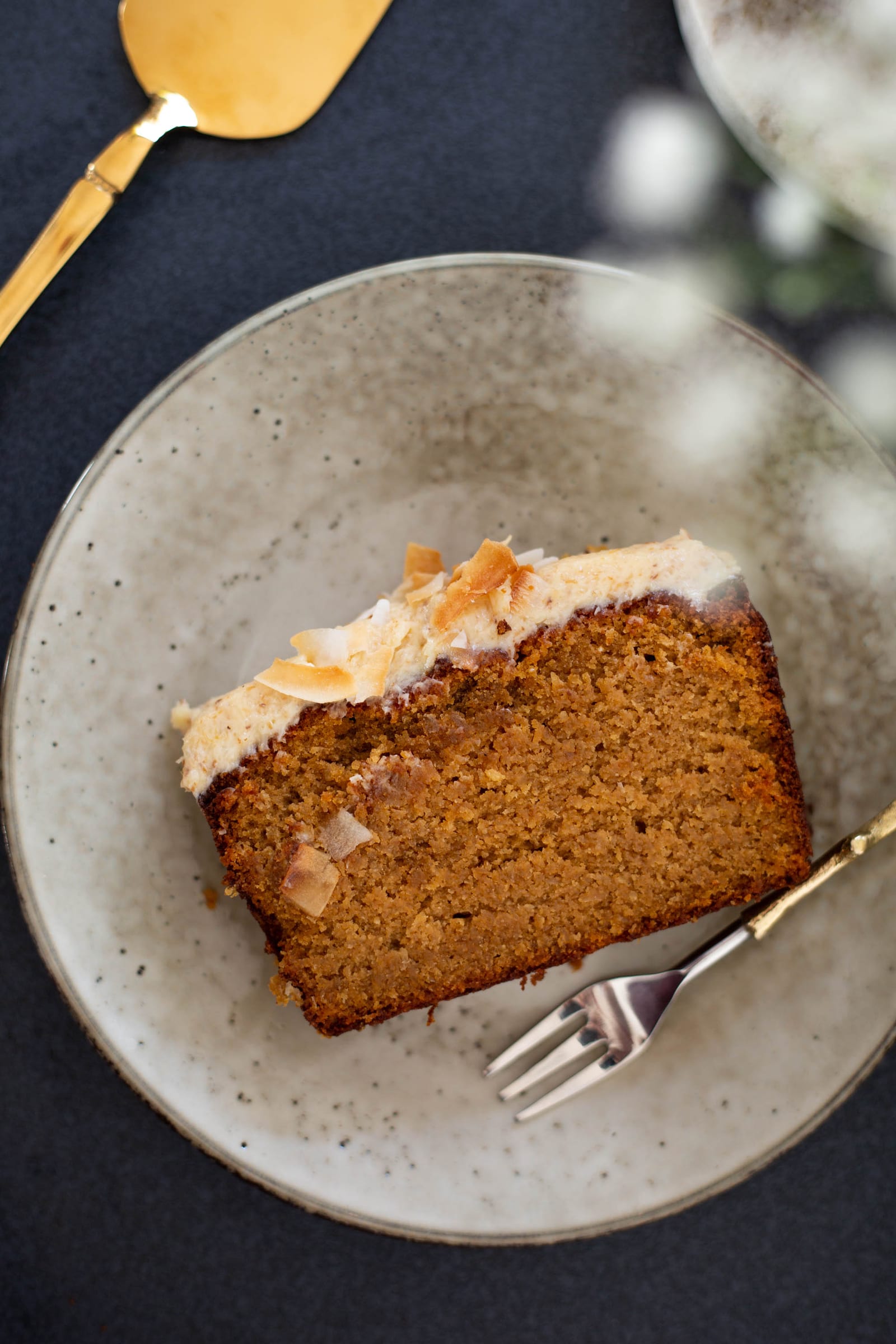 Close-up of a slice of gluten-free coconut loaf on a plate with a fork, from above