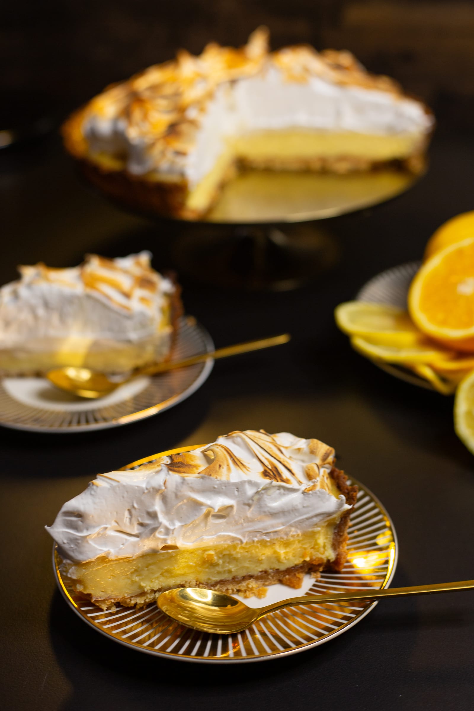 Slices of lemon meringue pie on plates, showing the lemon filling