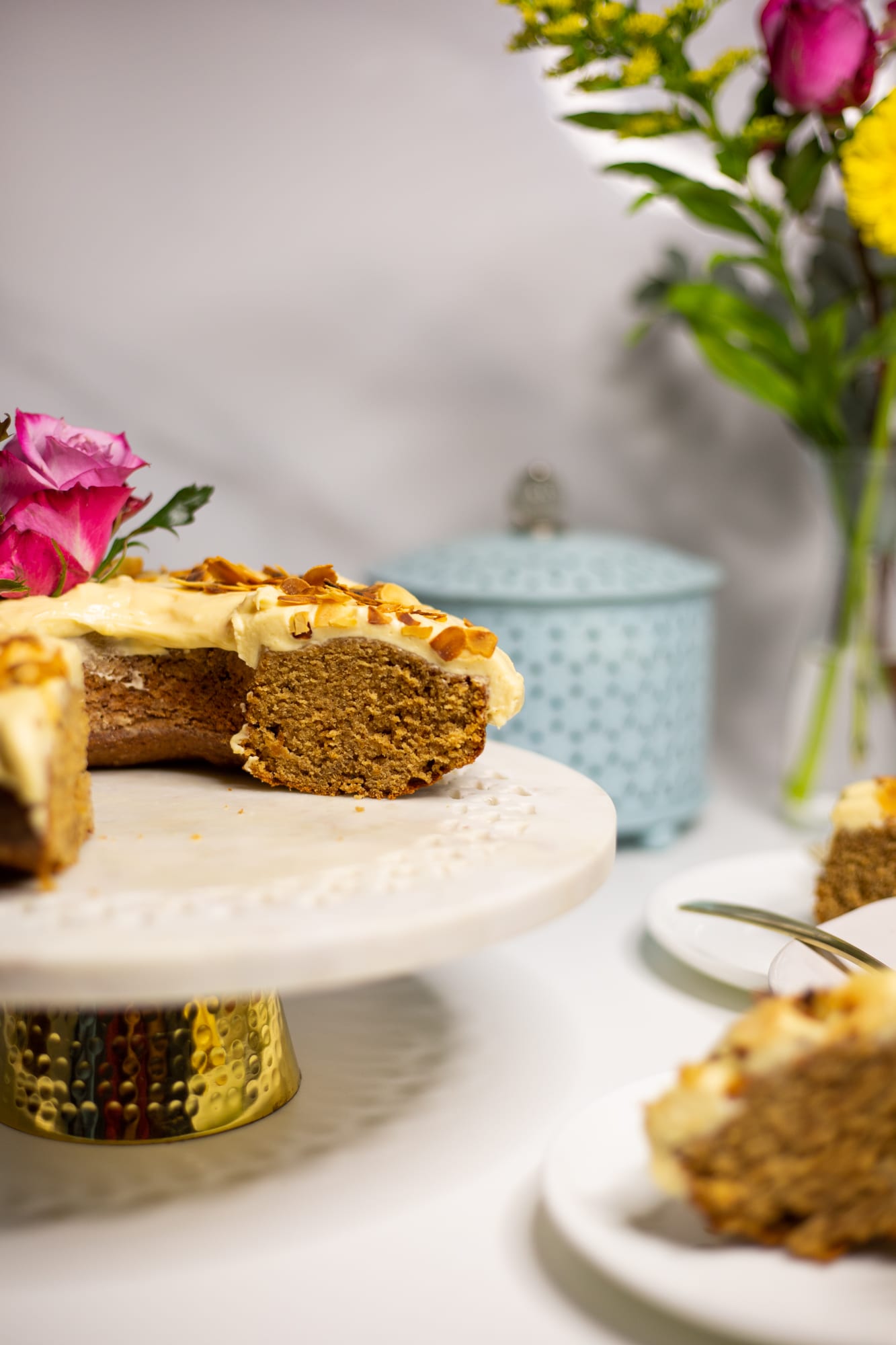 A cut citrus pound cake on its stand with a slice in front, showing the spiced crumb