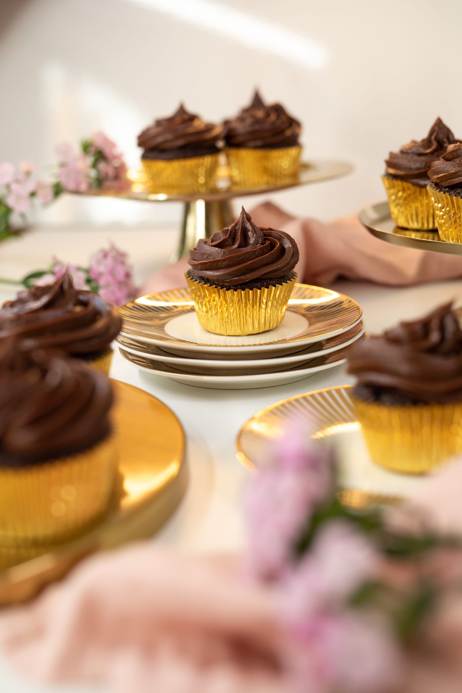 Ultimate triple chocolate cupcakes in gold cases on gold stands with pink flowers