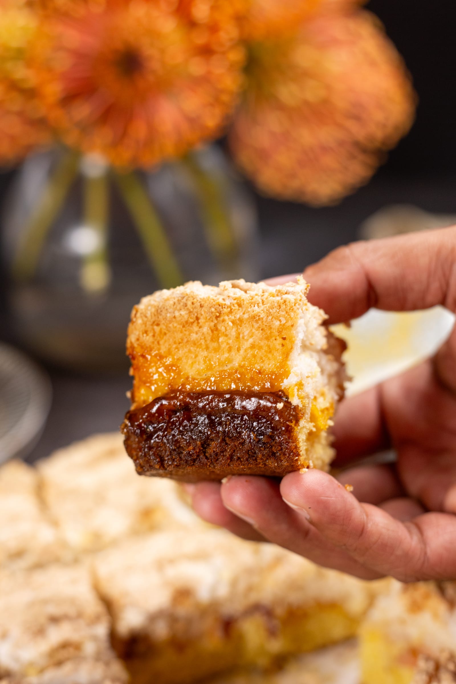 A hertzoggie square held up to show the layer of apricot jam