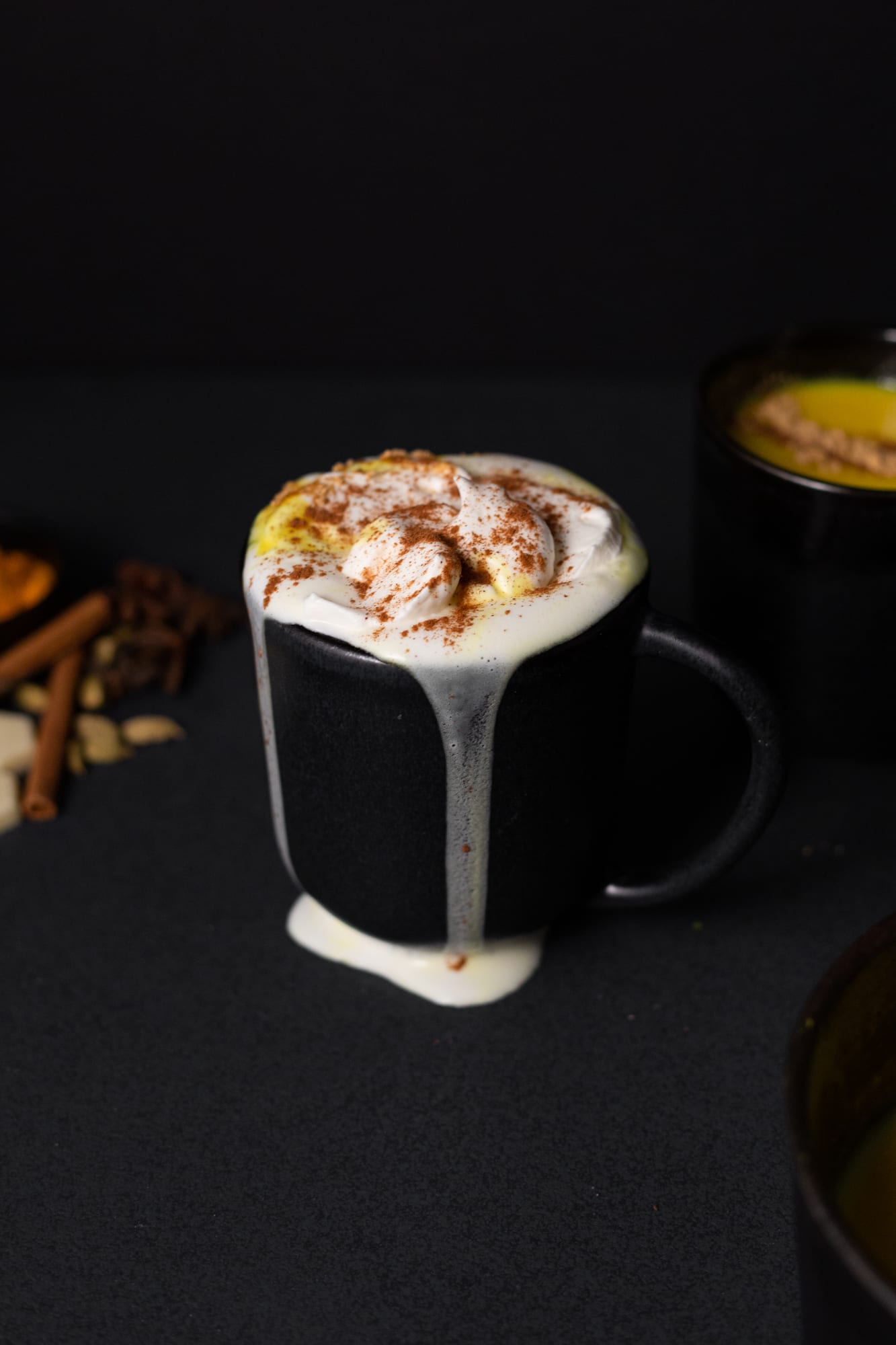 Whipped cream dripping down a mug of turmeric and ginger white hot chocolate